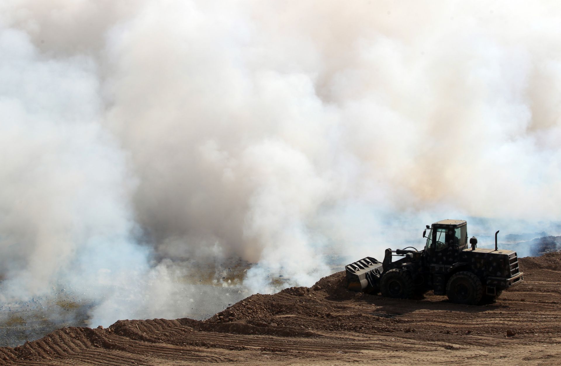 Iraqi forces attempt to extinguish a blaze set by the Islamic State in October 2016 south of Mosul.
