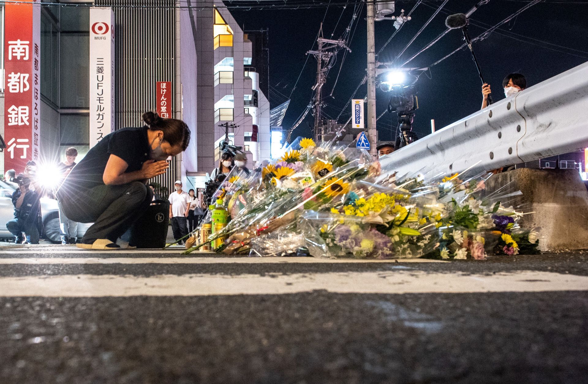 A woman mourns in front of a makeshift memorial outside the train station where former Japanese Prime Minister Shinzo Abe was shot and killed earlier in the day on July 8, 2022.