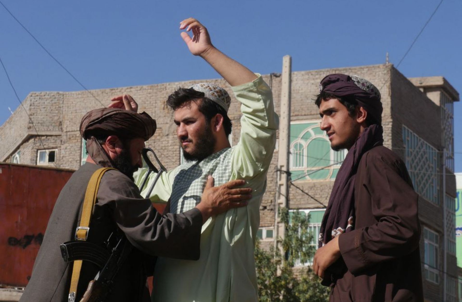 A Taliban fighter (L) frisks men at a checkpoint after a blast during Friday prayers Sept. 2, 2022, in Gazargah mosque in Herat.
