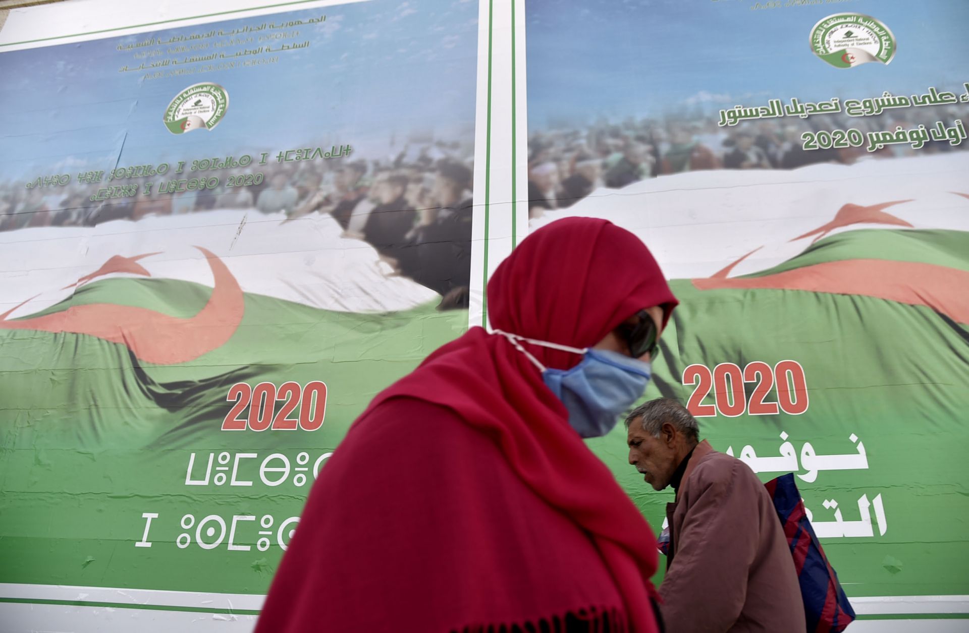 People walk past campaign billboards ahead of the upcoming constitutional referendum on a street in Algiers, Algeria, on Oct. 22, 2020. 