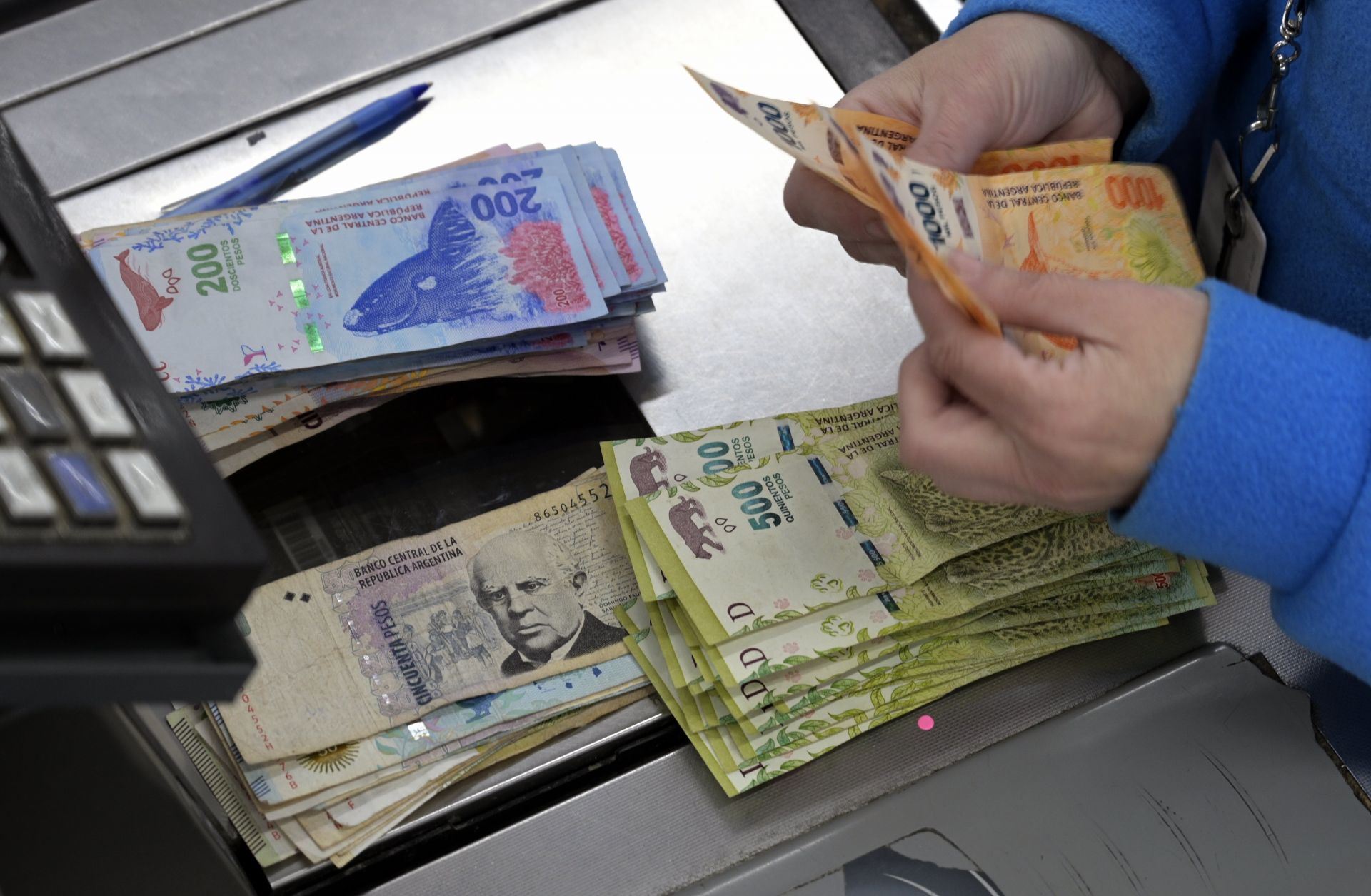 A supermarket cashier counts Argentine pesos in Buenos Aires on Aug. 15, 2019.