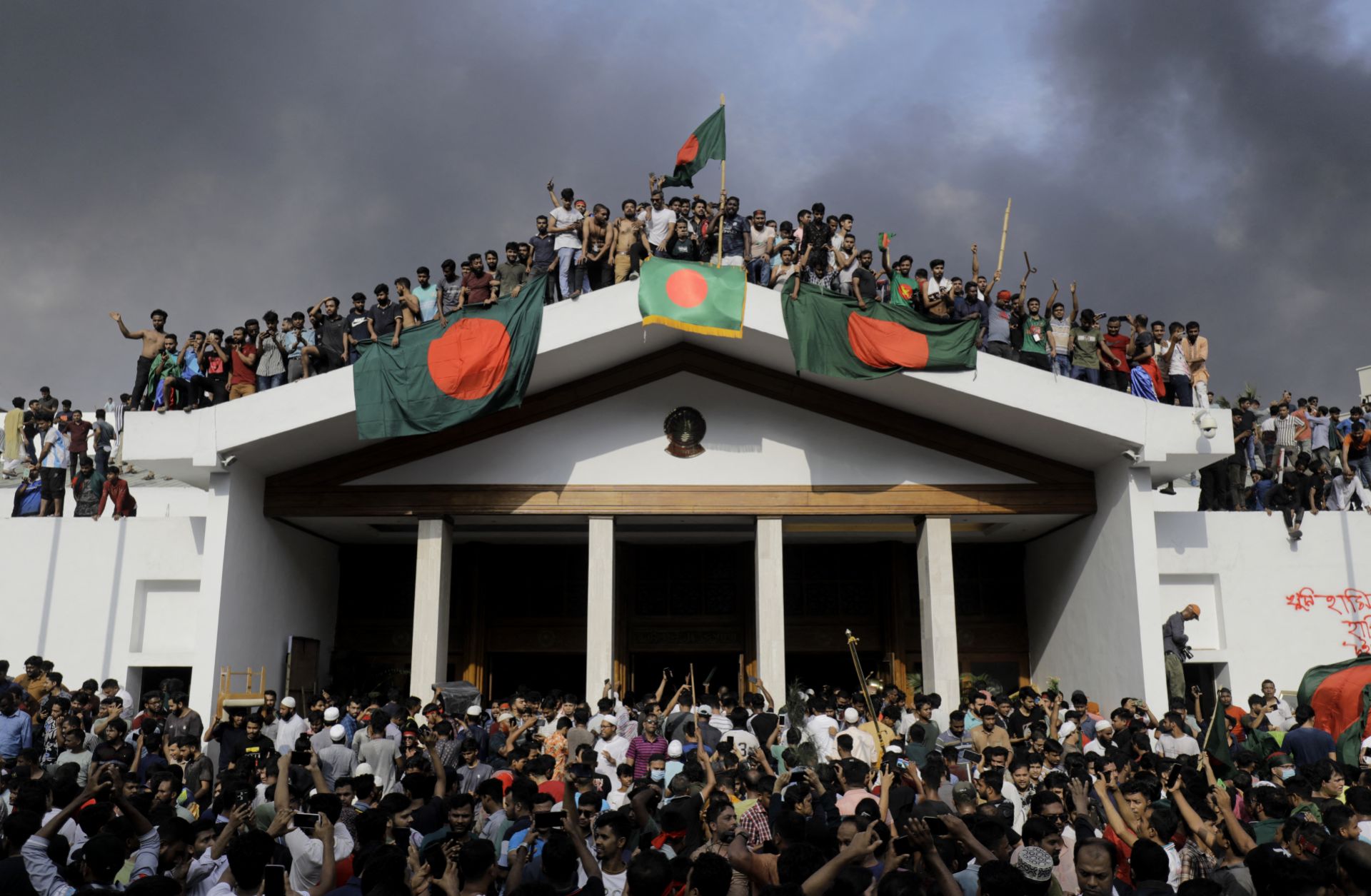 Anti-government protesters display Bangladesh's national flag as they storm Prime Minister Sheikh Hasina's palace in Dhaka on Aug. 5, 2024.