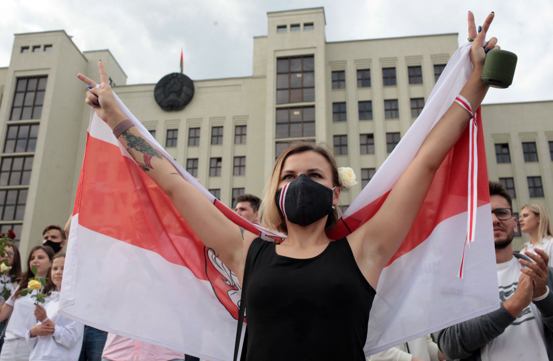 A woman wearing a face mask holds the former flag of Belarus at an anti-government protest in Minsk on Aug. 14, 2020. 