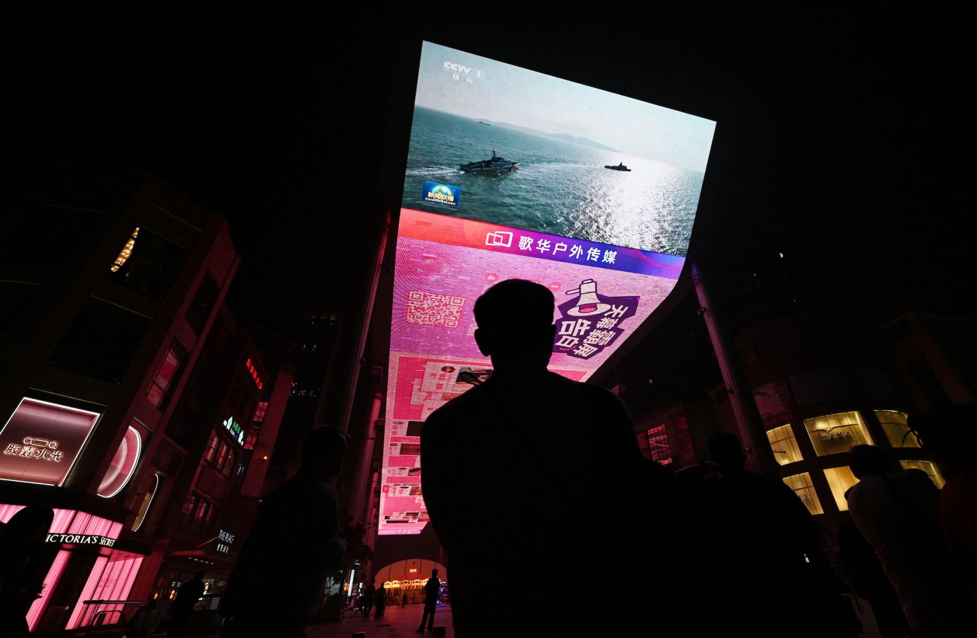 A man watches a news program about Chinese military drills surrounding Taiwan on a giant screen outside a shopping mall in Beijing on Oct. 14, 2024.