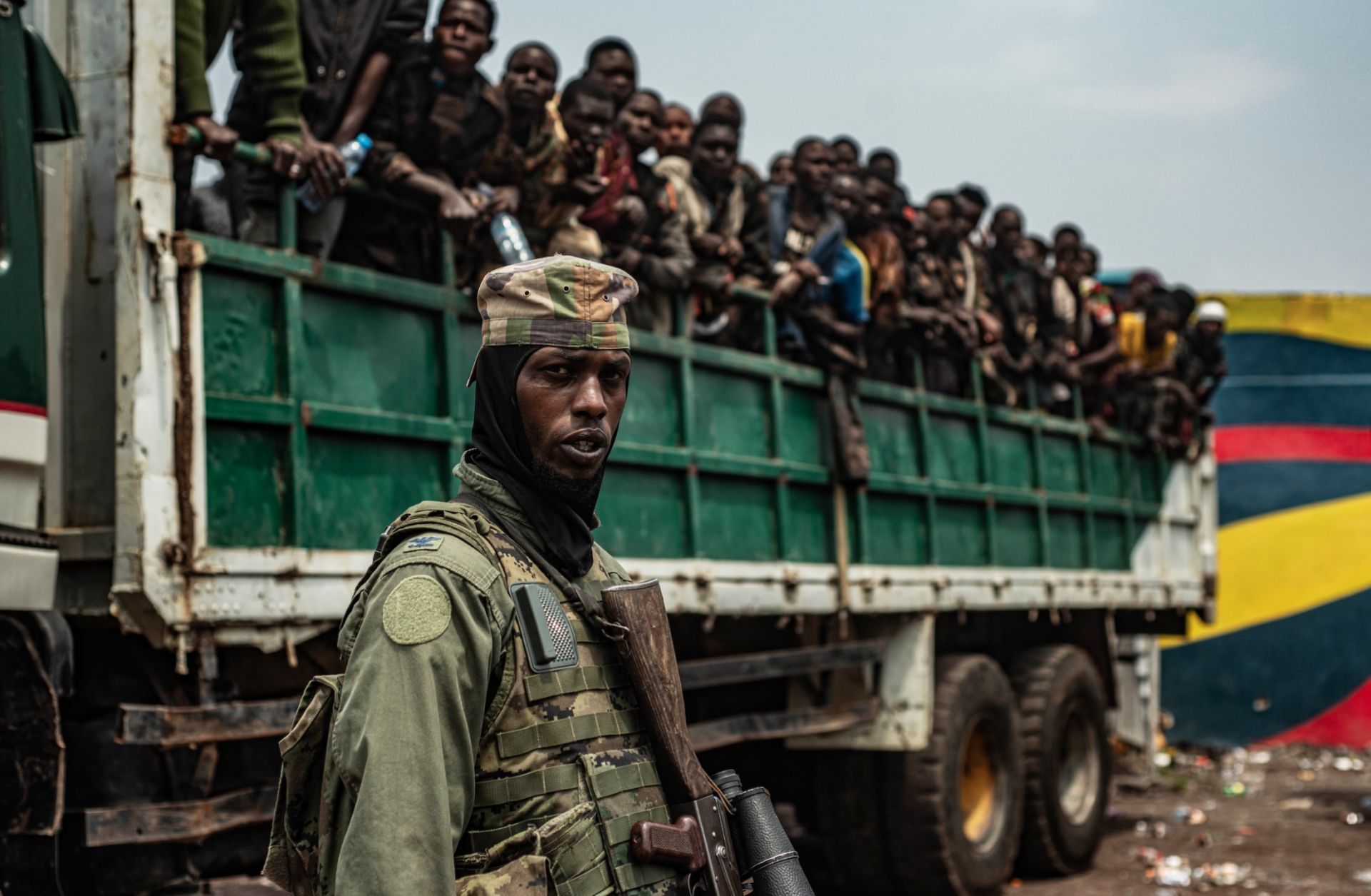 An M23 fighter stands in the foreground as detained Congolese soldiers are loaded onto trucks on Jan. 30, 2025, in Goma, Democratic Republic of Congo. 