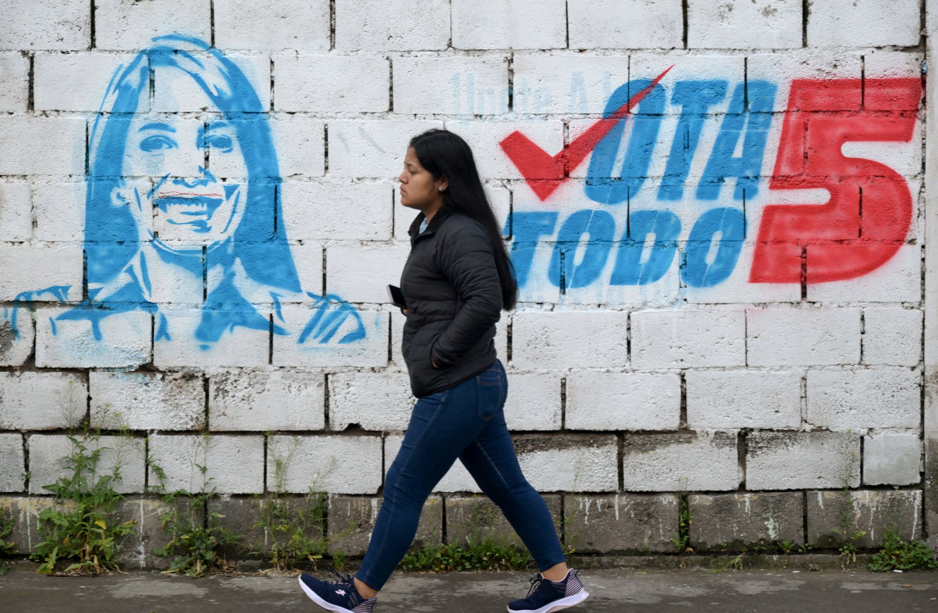 A woman walks past a mural of leftist presidential candidate Luisa Gonzalez in Quito, Ecuador, on Feb. 5, 2025.