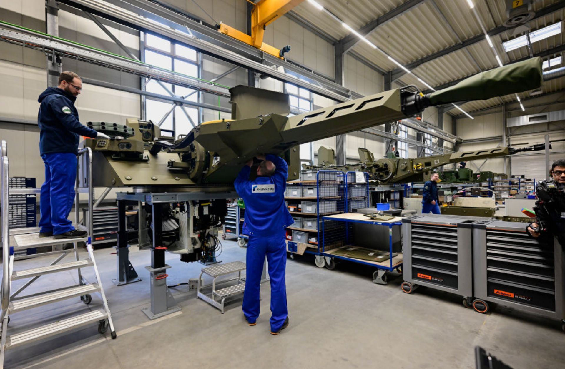 Employees work at a production line as German Chancellor Olaf Scholz and Defence Minister Boris Pistorius attend the groundbreaking ceremony for a new munitions factory of German defense contractor Rheinmetall on Feb. 12, 2024, in Unterluess, Germany.