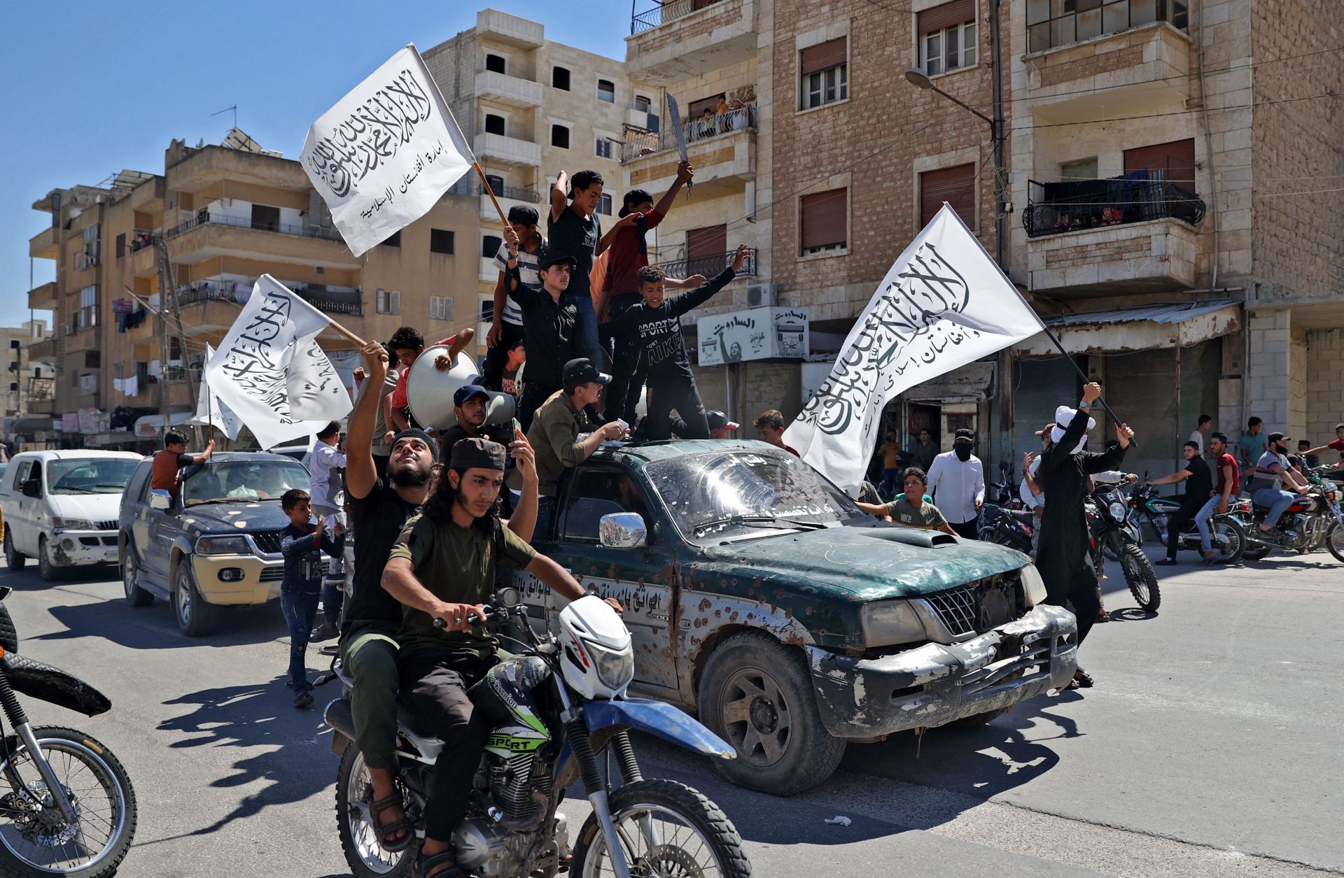 Members of Syria's top jihadist group, the al Quada-linked Hayat Tahrir al-Sham, parade through the city of Idlib on Aug. 20, 2021, in celebration of the Taliban's takeover of Afghanistan.