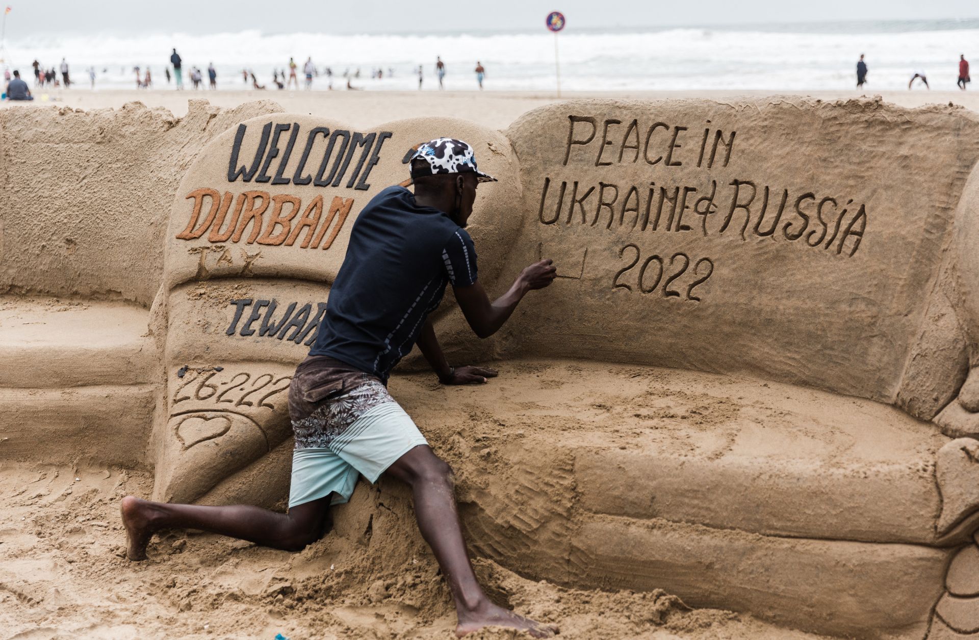 A sand sculptor writes a message calling for peace between Ukraine and Russia on a beach in Durban, South Africa, on Feb. 27, 2022. 