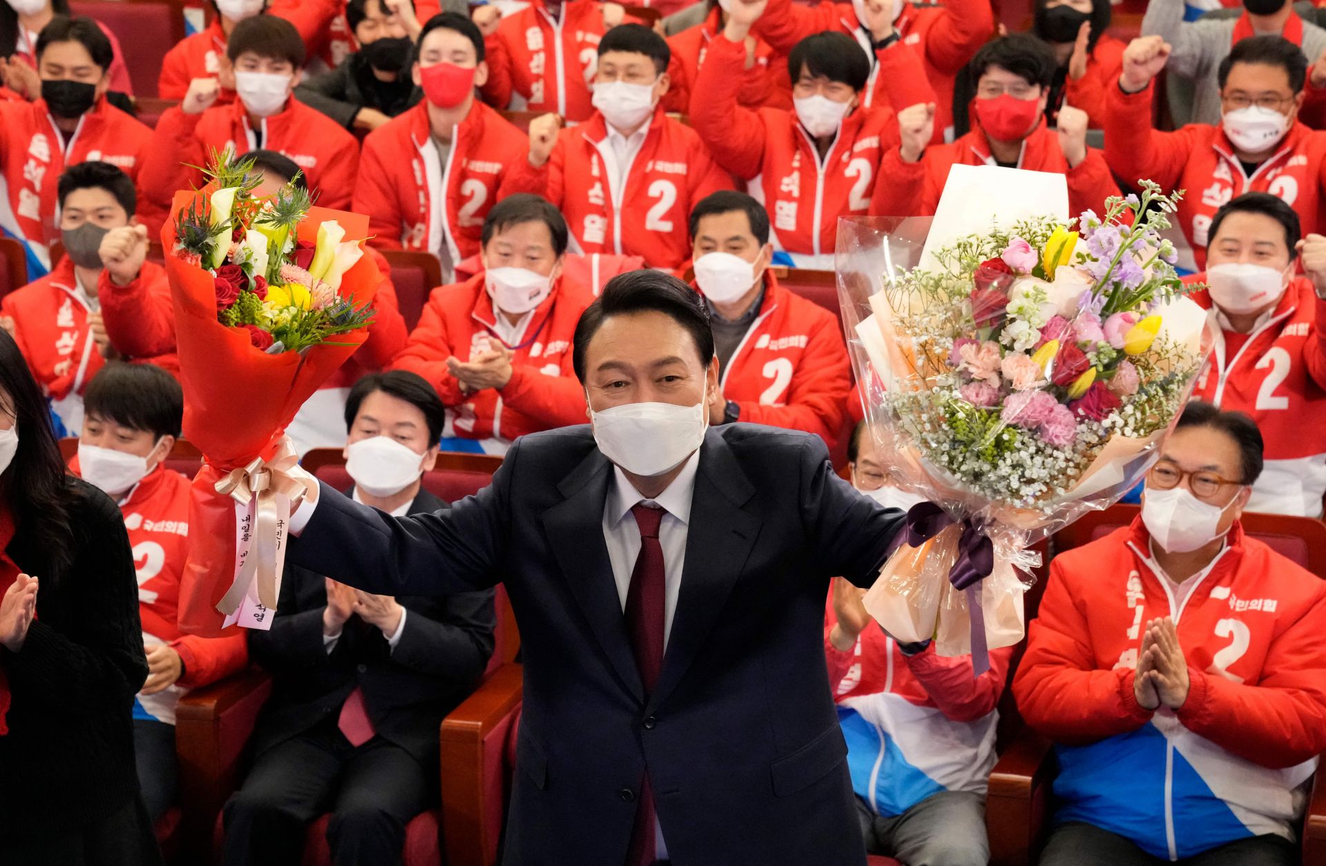 South Korean President-elect Yoon Suk Yeol holds bouquets as he is congratulated by members of his People Power Party at the National Assembly in Seoul, South Korea, on March 10, 2022.