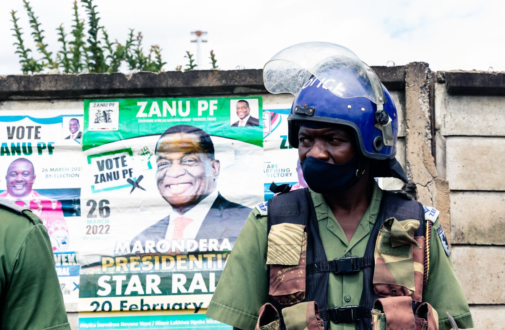 A police officer stands in front of an election poster for Zimbabwean President Emmerson Mnangagwa as he patrols outside a stadium where opposition leader Nelson Chamisa was holding a campaign rally in Marondera, Zimbabwe, on March 12, 2022. 