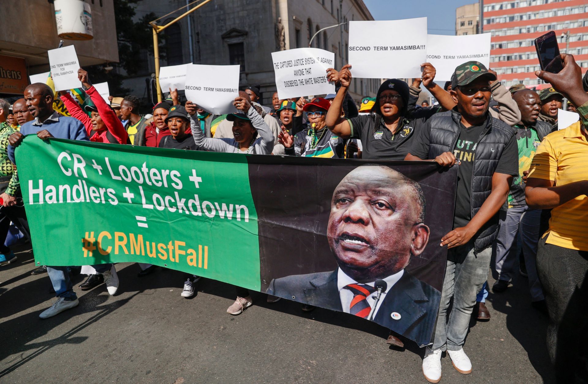 Disgruntled members of South Africa’s ruling African National Congress (ANC) party march to the party’s headquarters in Johannesburg, holding a poster reflecting the face of South African President Cyril Ramaphosa, on July 15, 2022.