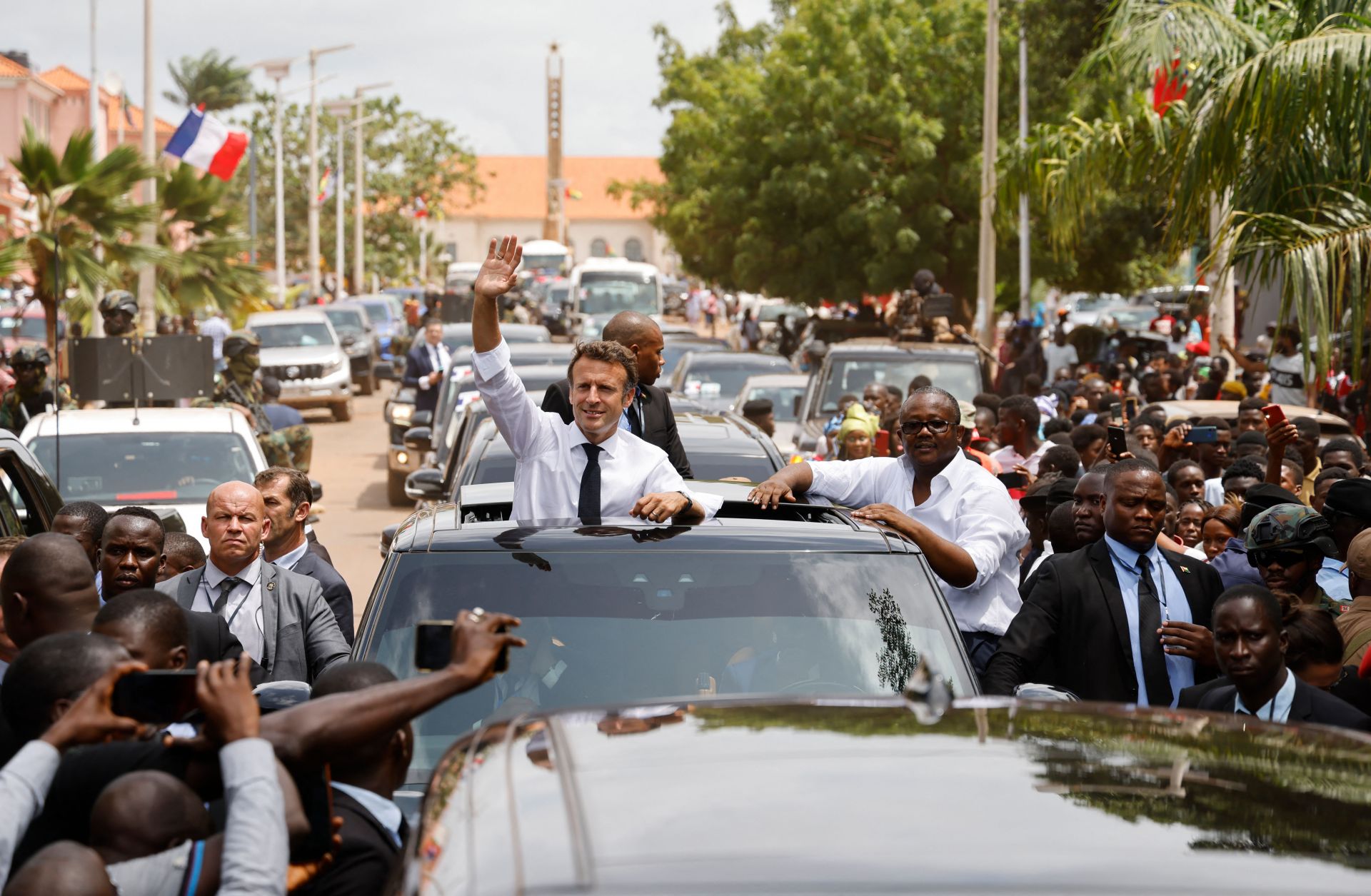 During the final day of the African tour that also included visits to Cameroon and Benin, French President Emmanuel Macron (left) waves to a crowd through the roof of a car in Bissau with Guinea-Bissau's President Umaro Sissoco Embalo. 