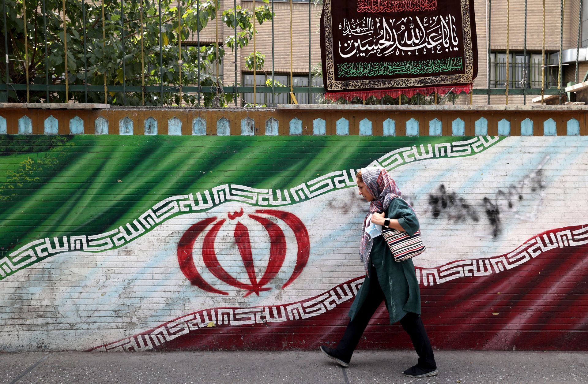 A woman walks past a mural in Tehran, Iran, on July 31, 2022.