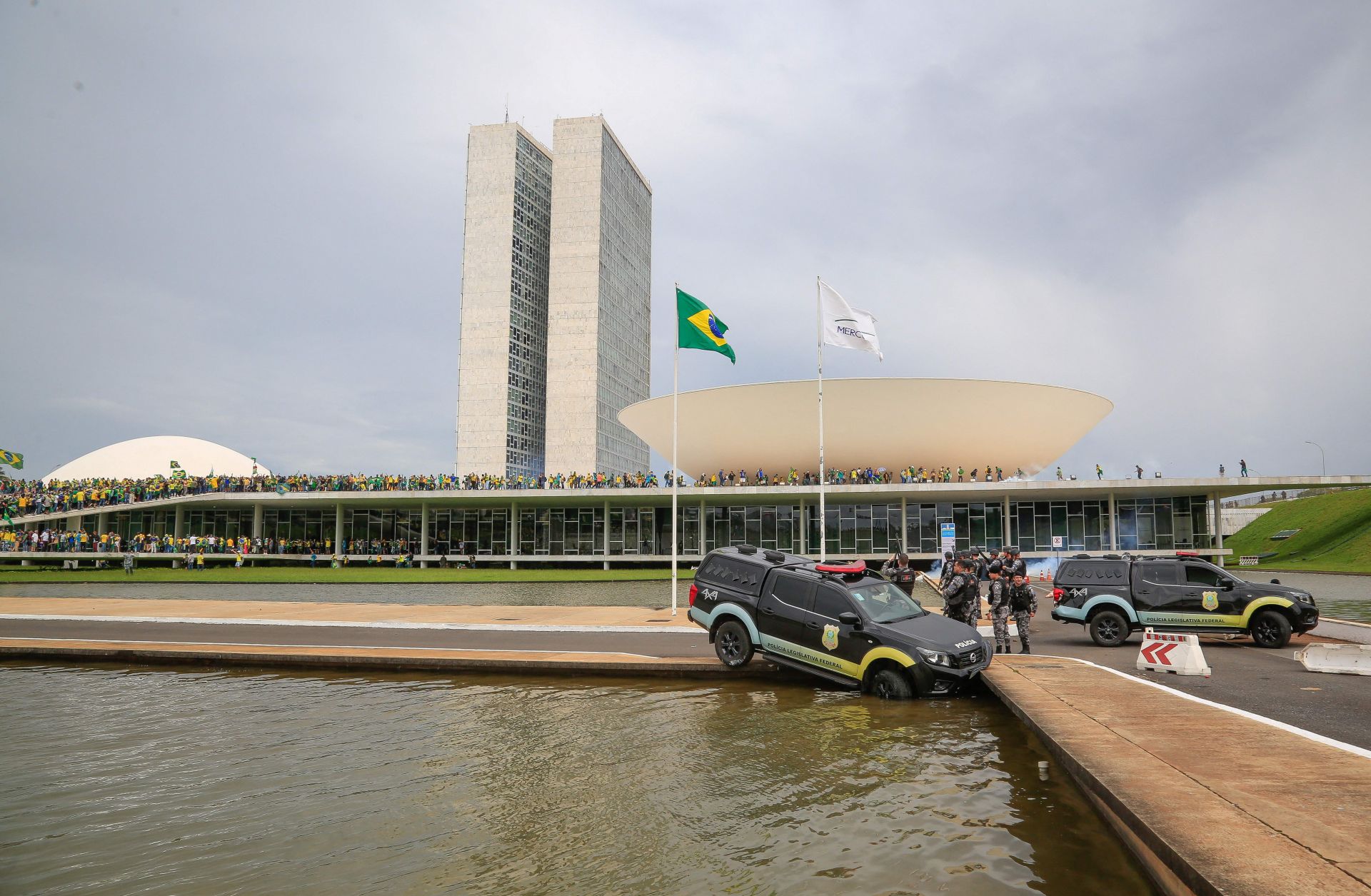 Members of Brazil’s Federal Legislative Police stand next to a vehicle that crashed into a fountain as supporters of former President Jair Bolsonaro invade the National Congress in Brasilia on Jan. 8, 2023. 