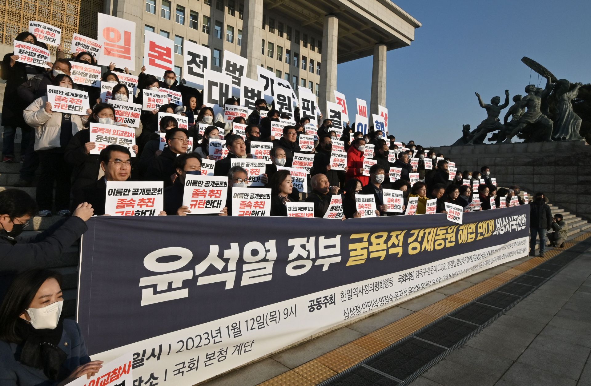 South Korean opposition lawmakers and supporters of the victims of Japan's wartime forced labor hold up placards during a protest against a public hearing on the issue at the National Assembly in Seoul on Jan. 12, 2023. 