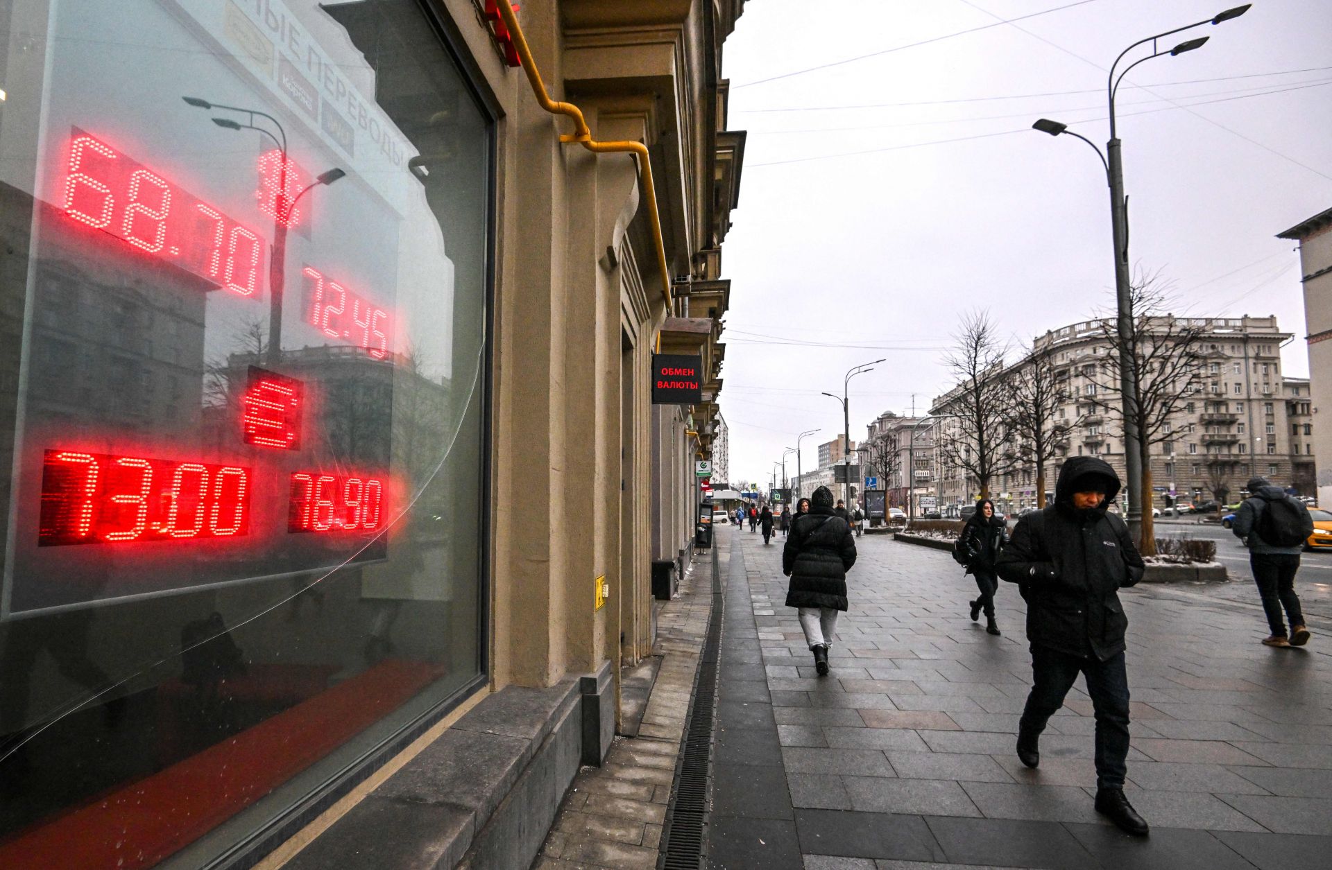 Pedestrians walk past a board at a currency exchange office in Moscow, Russia, on Jan. 16, 2023. 