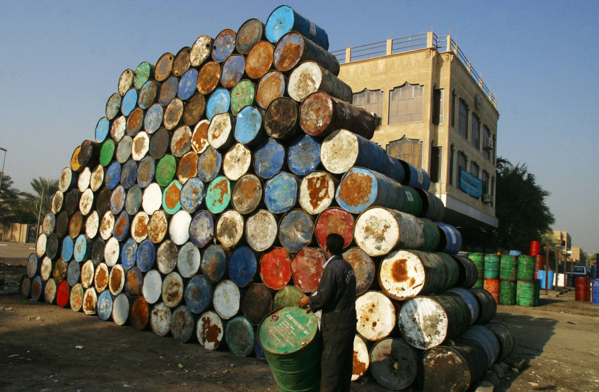 A worker surveys a stack of empty oil drums as he brings another to add to it at a warehouse in Baghdad, Iraq, on Jan. 6, 2004.