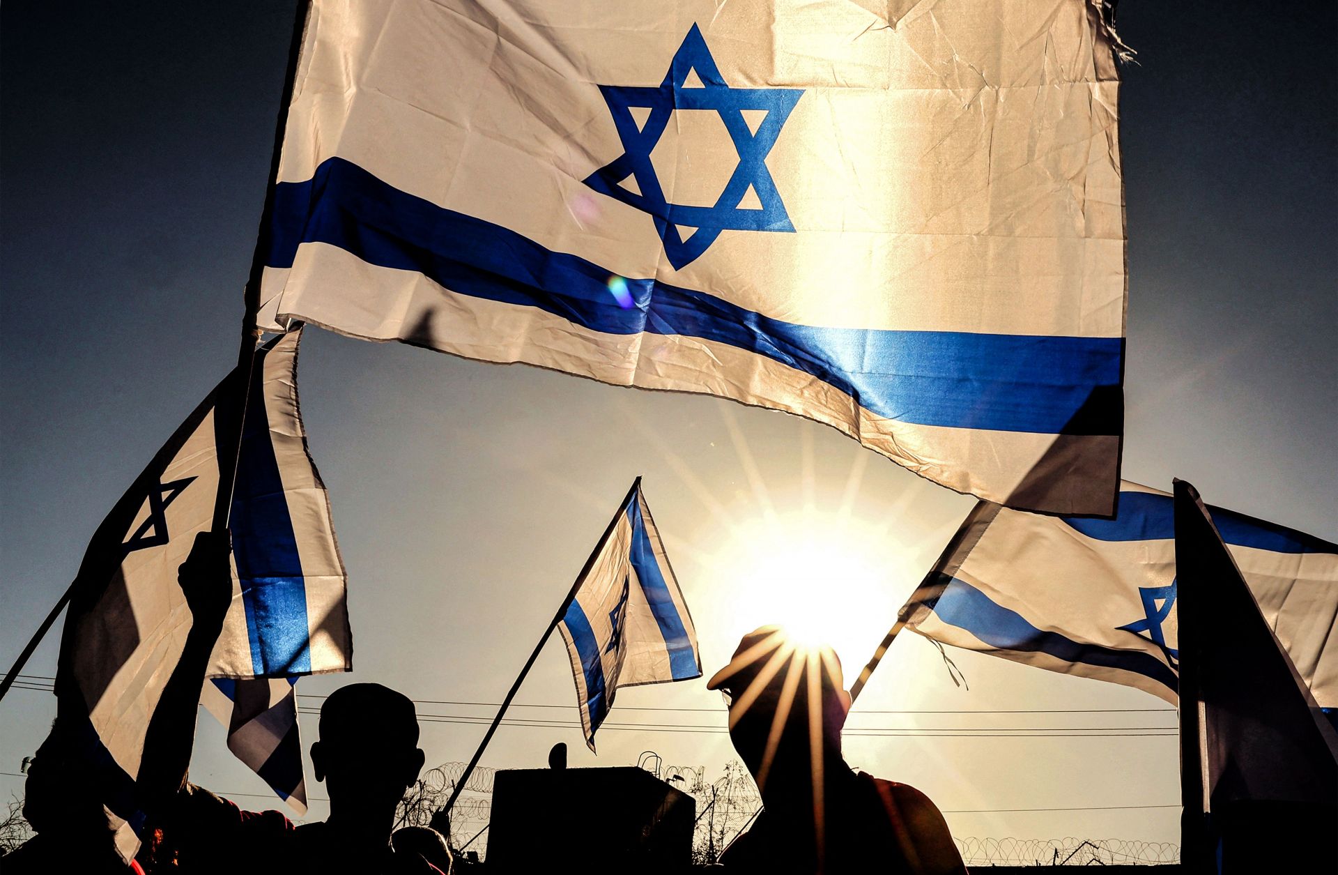 Israeli military veterans wave national flags during a rally against the government's judicial reform bill along a highway near Netanya on March 28, 2023.