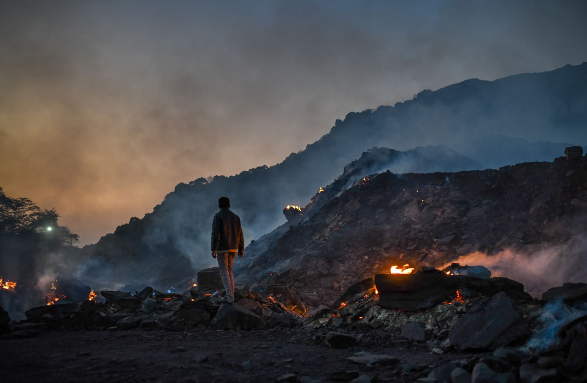 A man stands near burning waste at a coal mine in Sonbhadra, India, on Nov. 22, 2021. High oil and gas prices amid the war in Ukraine risks making India, the world’s second-largest coal consumer, even more reliant on the cheapest (and dirtiest) fossil fuel.