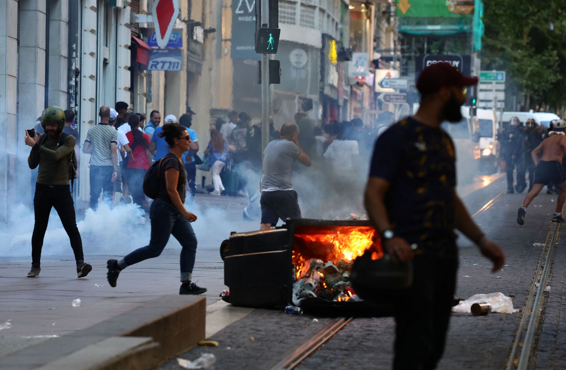 Protesters run from launched tear gas canisters during clashes with police in Marseille, southern France, on July 1, 2023, after a fourth consecutive night of rioting over the killing of a teenager by police.