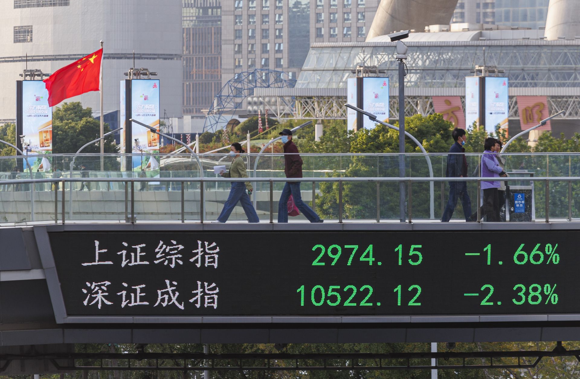 People walk on a pedestrian bridge that displays the numbers for the Shanghai Shenzhen stock indexes on Oct. 10, 2022, in Shanghai, China. 