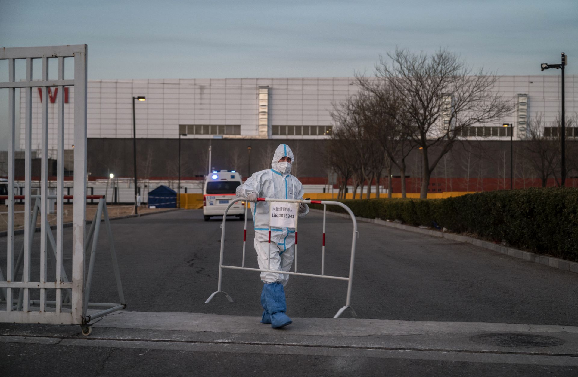 A worker places a barricade on a road after allowing an ambulance to enter a COVID-19 quarantine facility in Beijing, China, on Dec. 7, 2022. 