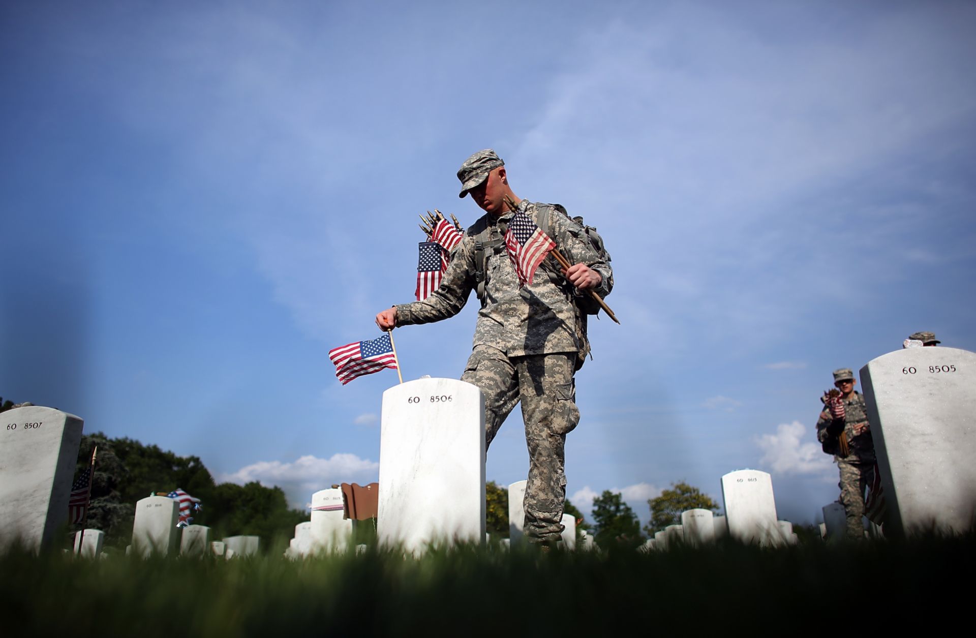 A soldier places flags at the gravesites of U.S. military members buried at the Arlington National Cemetery in Virginia on May 24, 2012. 