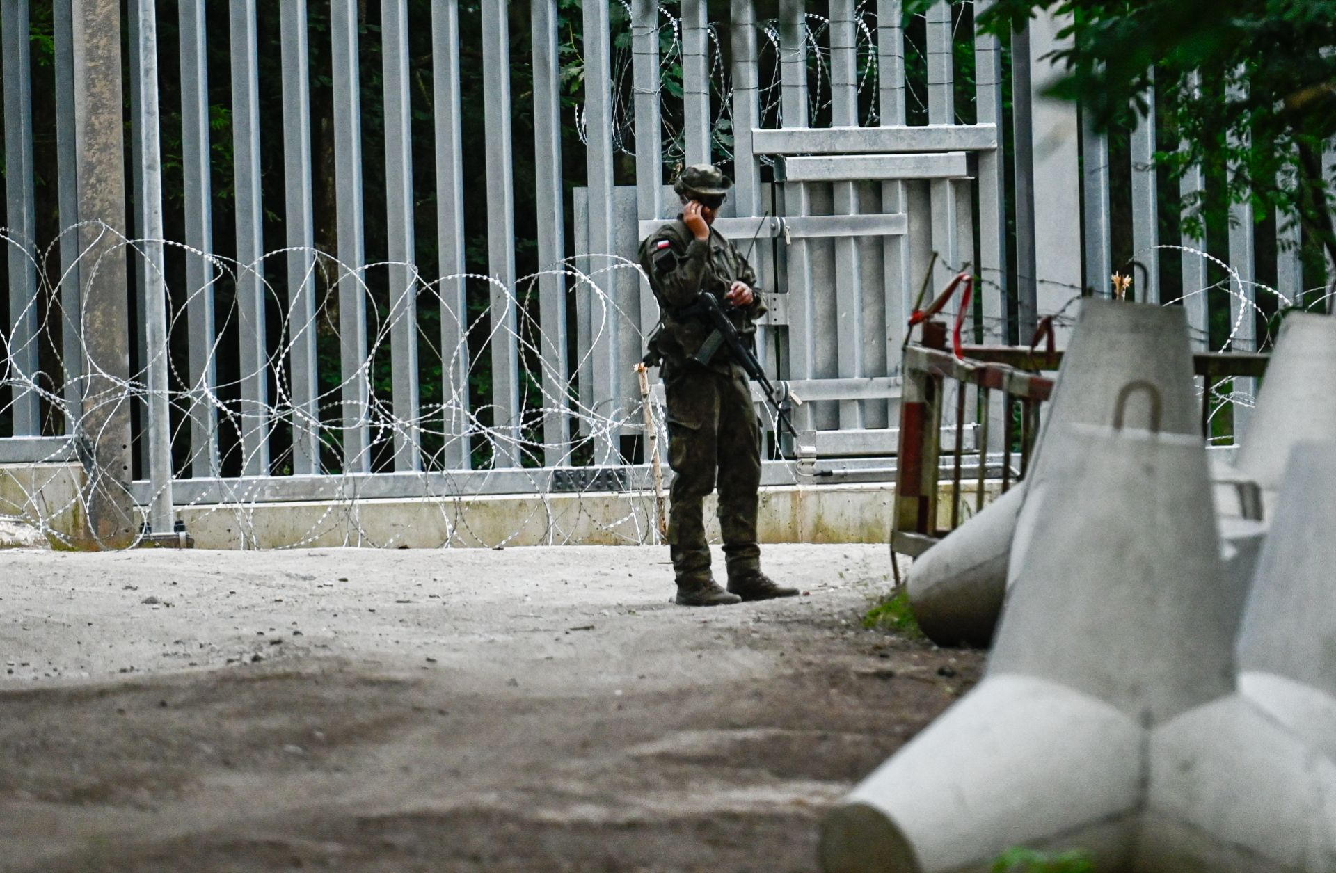 A Polish soldier stands by anti-tank obstacles by the metal wall constructed at the Belarussian border in Bialowieza, Poland, on July 08, 2023. 