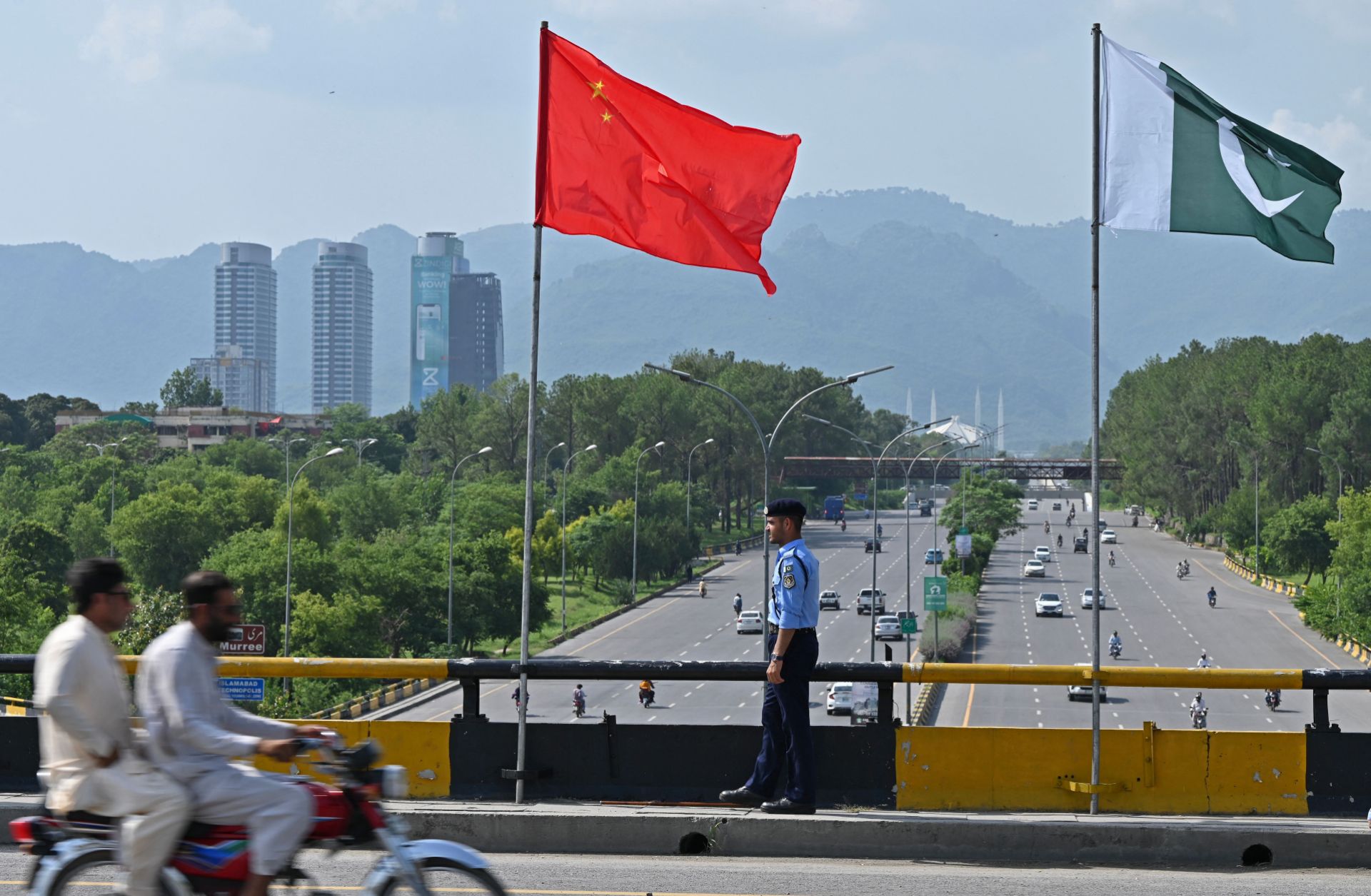 A policeman stands under Chinese and Pakistani flags along a road in Islamabad ahead of Chinese Vice Premier He Lifeng's visit on July 30, 2023.