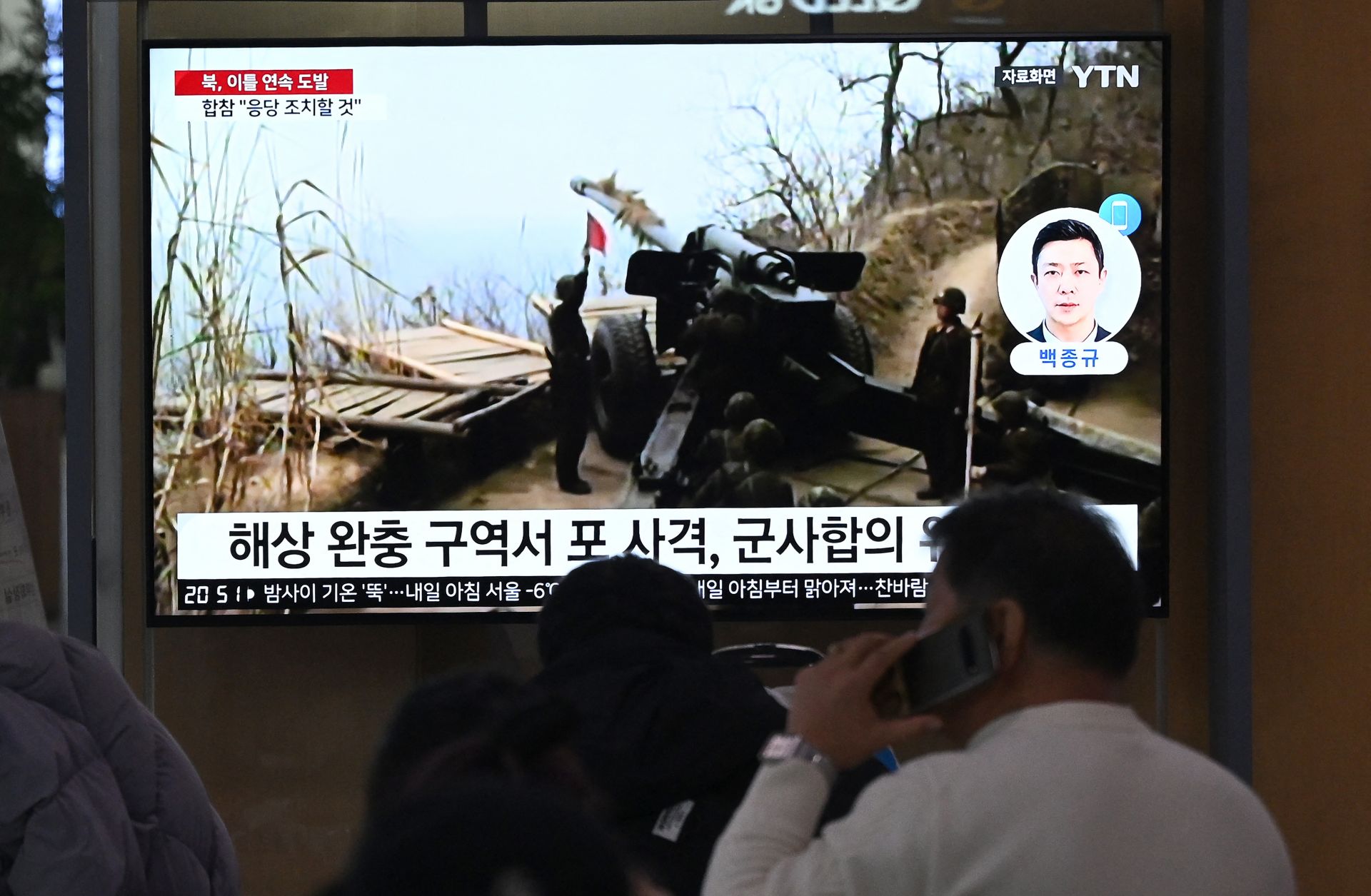 People watch a television screen showing a news broadcast with file footage of North Korea's artillery firing, at a railway station in Seoul on Jan. 6, 2024.