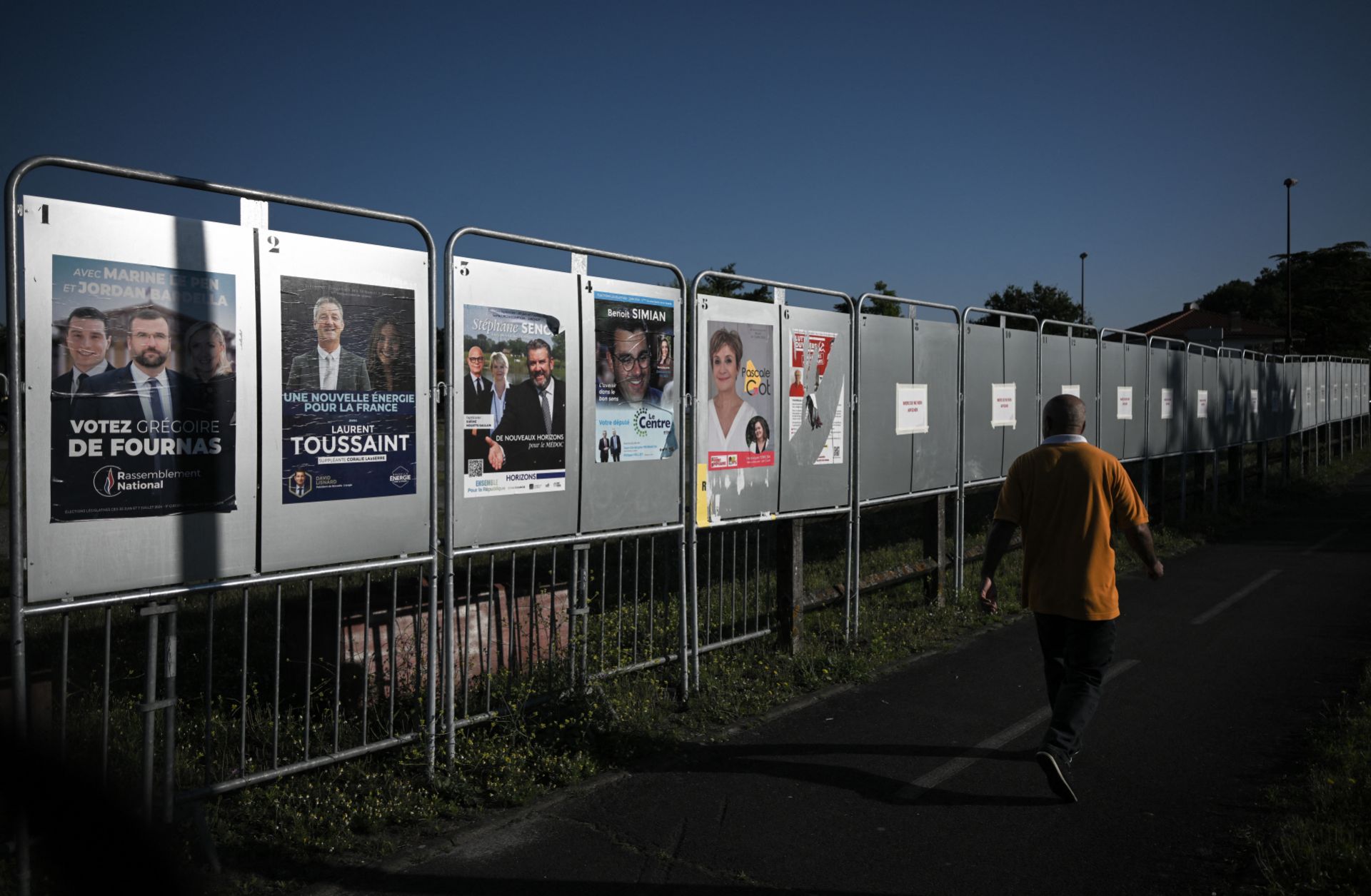 A man walks past campaign posters for France's upcoming legislative elections in Parempuyre, southwestern France, on June 25, 2024.