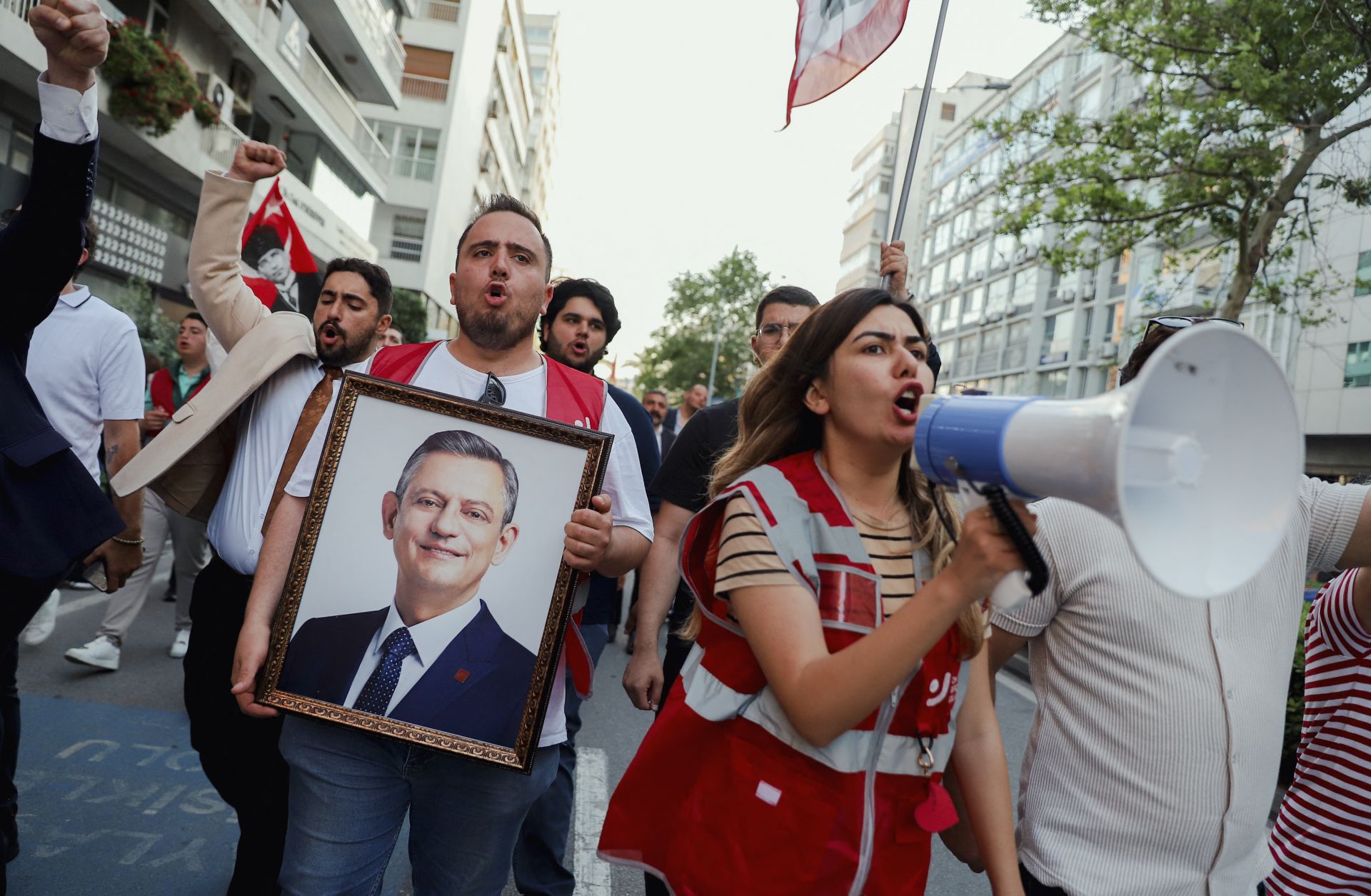 Demonstrators yell through a megaphone and hold a framed portrait of the ousted Republican People's Party (CHP) chairman, Ogur Ozel, during an opposition rally in Izmir, Turkey, on May 24, 2026. 