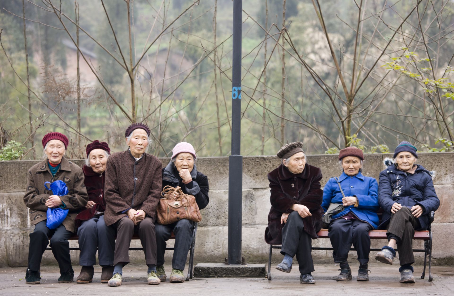 Elderly women sit together on benches in Chongqing, China.