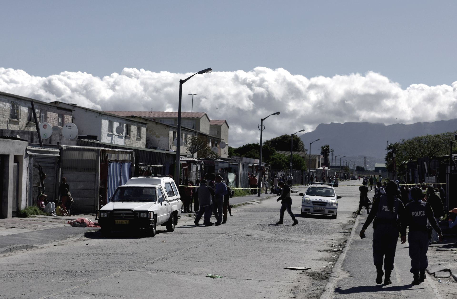 Residents gather as South African police officers respond to a shooting of two alleged gang members in Cape Town in 2017.