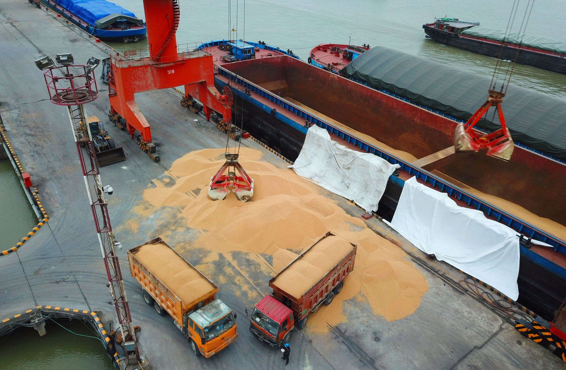 Trucks laden with imported soybeans prepare to depart a port in eastern China in April 2018. In 2017, Brazil supplied more than half of China's imported soybeans. Trucks laden with imported soybeans prepare to depart a port in eastern China in April 2018.
