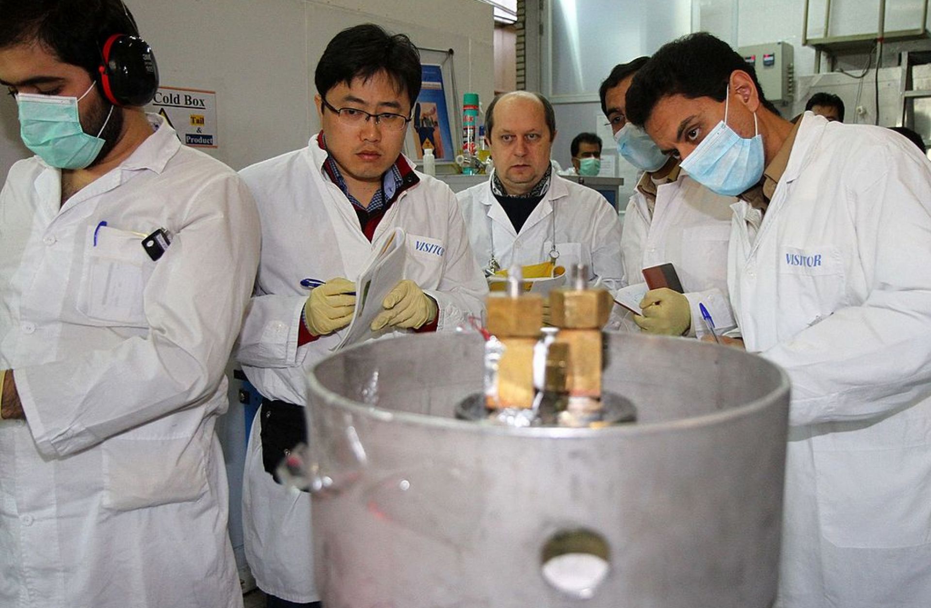 IAEA inspectors (2nd, 3rd L) and Iranian technicians disconnect the connections between the twin cascades for 20 percent uranium production at nuclear power plant of Natanz, Iran, on Jan., 20, 2014.