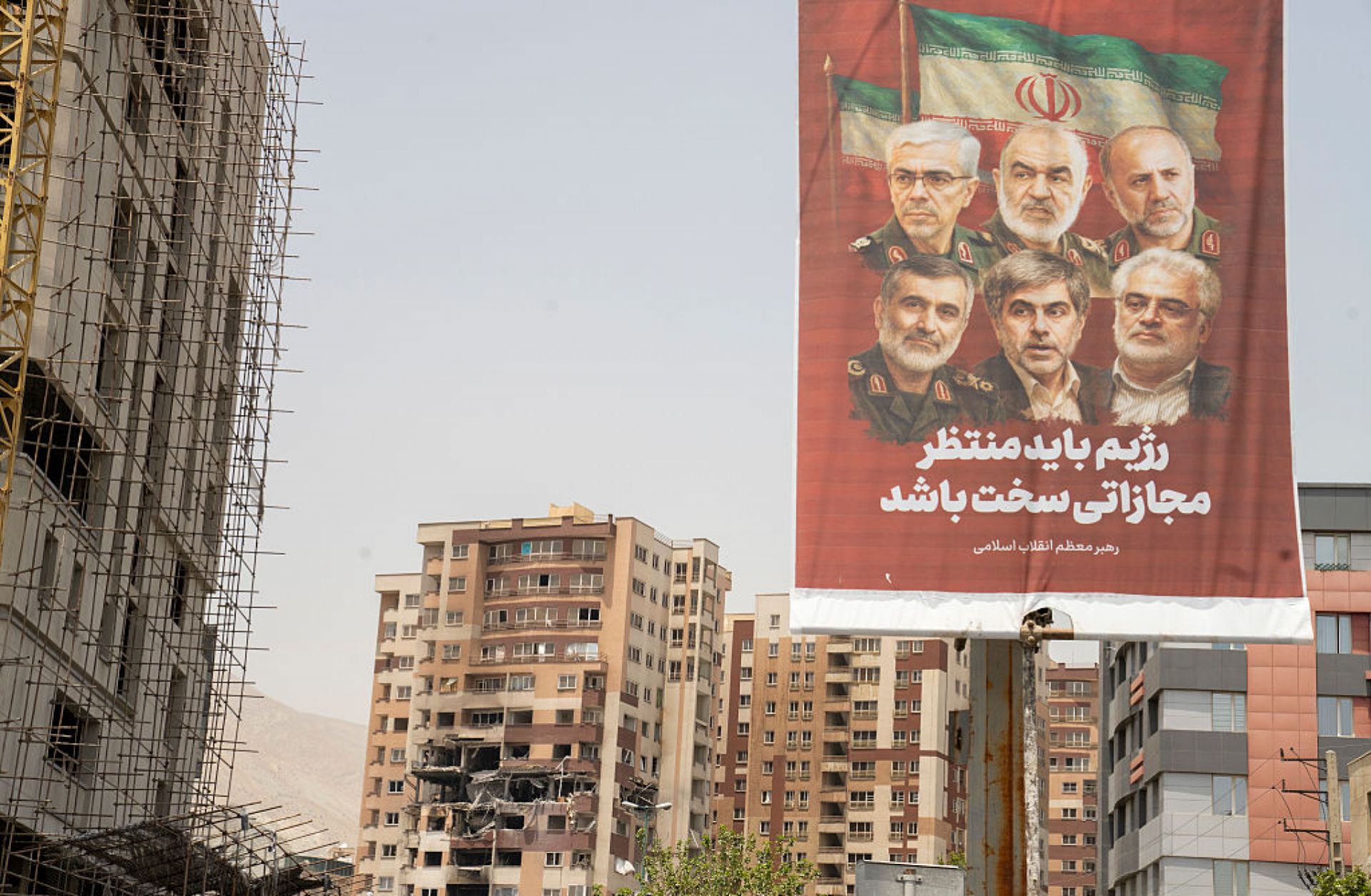 A photo taken in Tehran, Iran, on June 26, 2025, shows an Iranian political banner hanging near the remains of a residential building struck by an Israeli attack. 