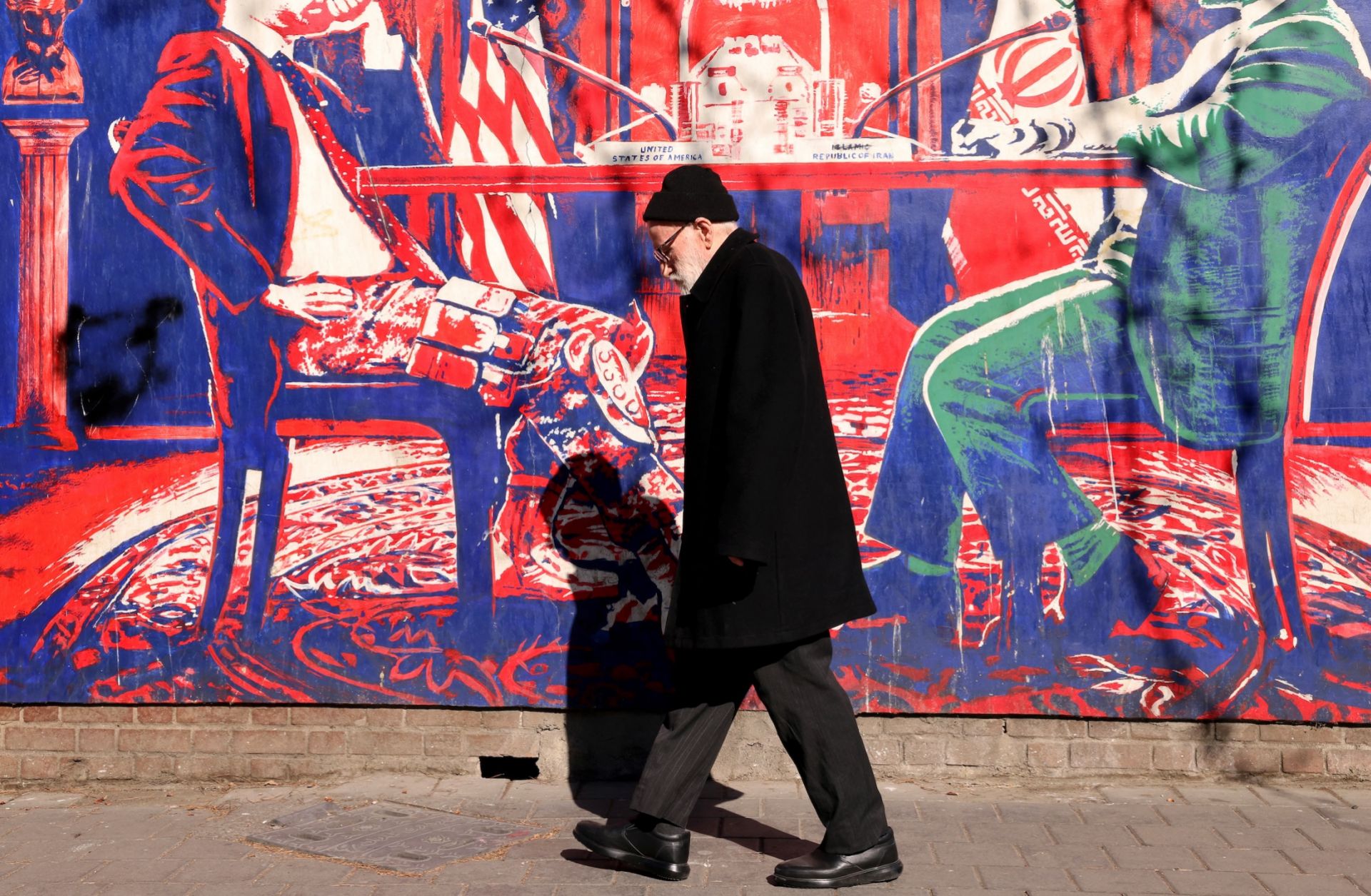 A man walks past a mural painted on the outer walls of the former U.S. embassy in Tehran, Iran, on Feb. 1, 2026.