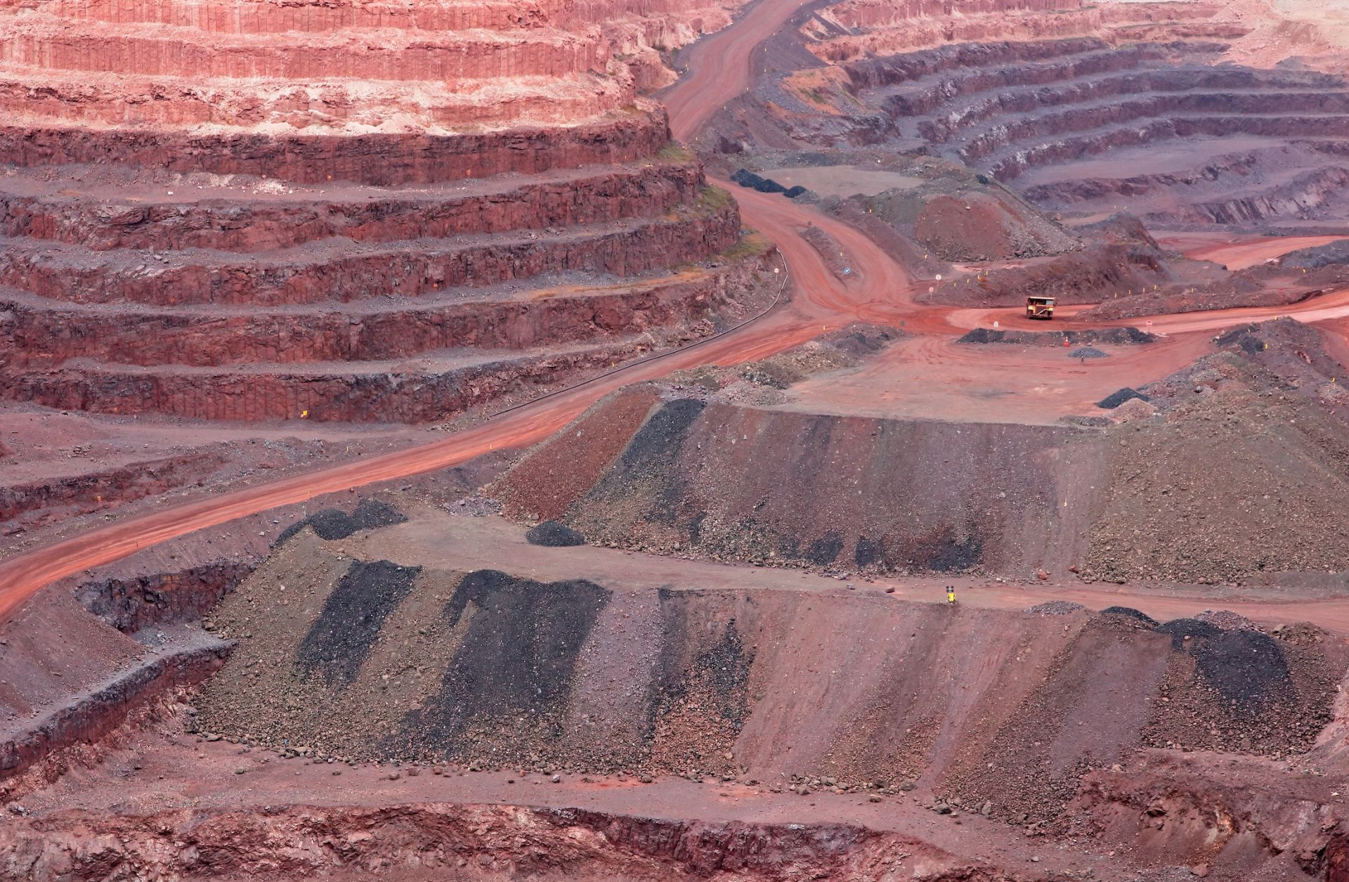 A stock photo shows a large, open-pit iron ore mine with various layers of soil.