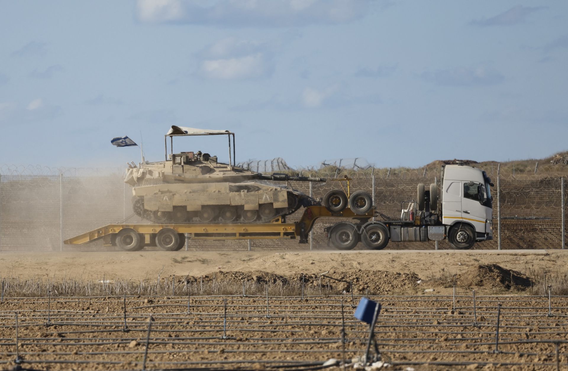An Israeli military truck carries a tank in southern Israel on the border with the Gaza Strip, on Oct. 14, 2025.