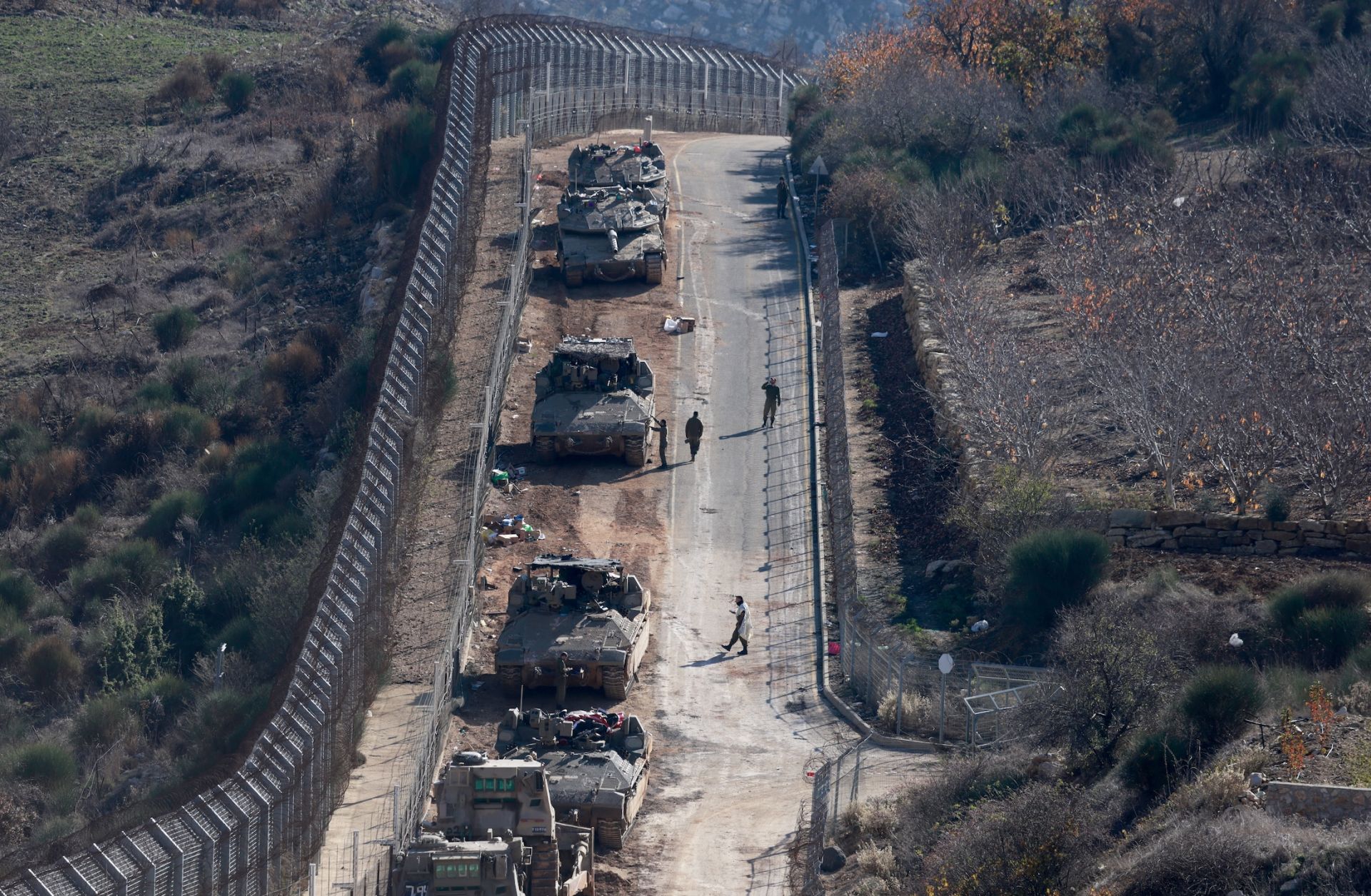 Israeli tanks and armored vehicles line up the area outside the Druze village of Majdal Shams on the fence with the buffer zone that separates the Israeli-annexed Golan Heights from the rest of Syria on Dec. 9, 2024.