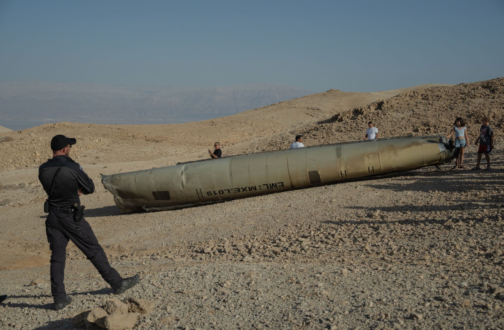 An Israeli police officer stands near the remains of an Iranian missile on Oct. 2, 2024, near the Dead Sea, Israel. 