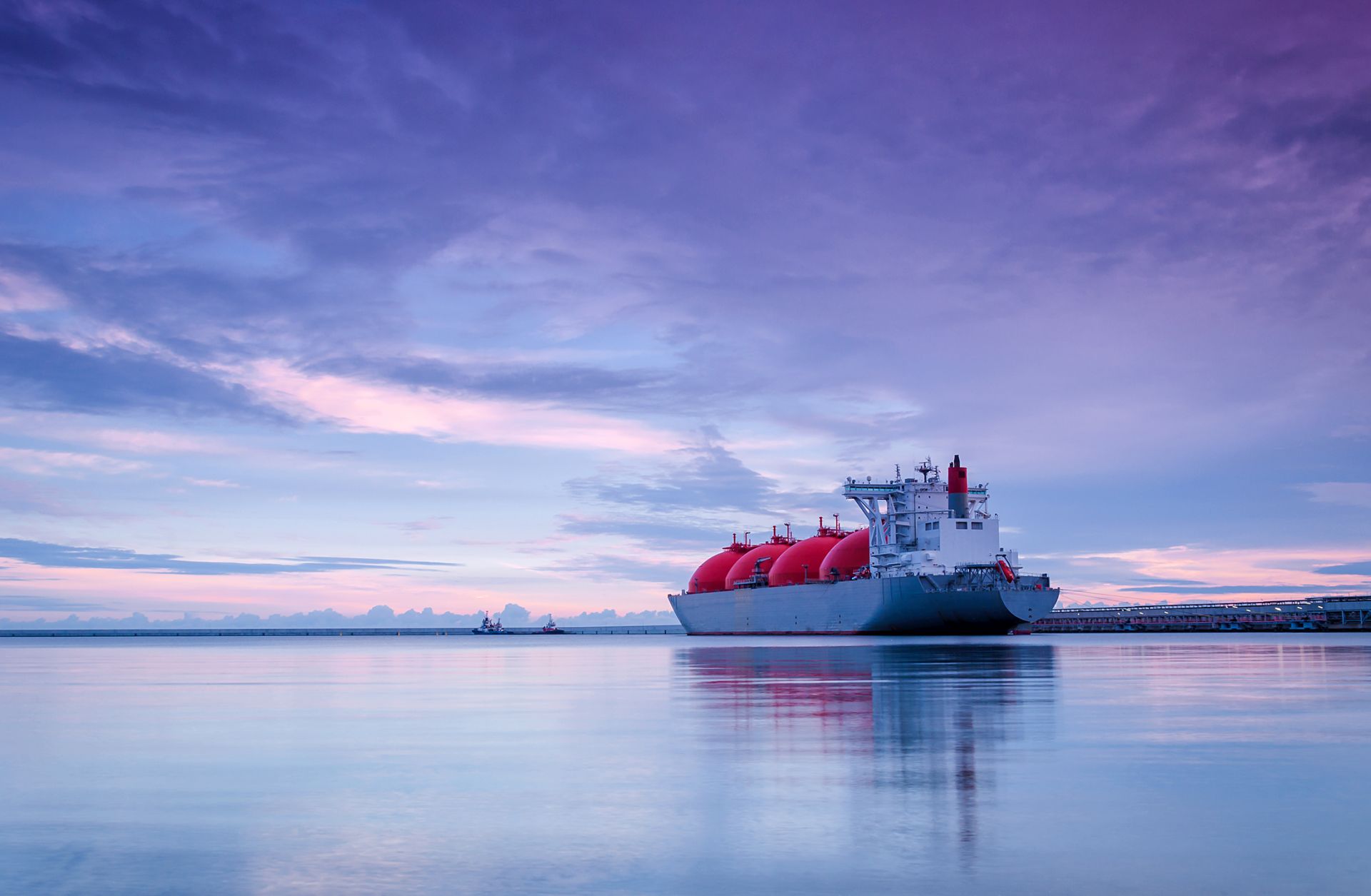 The sun rises over an LNG terminal at sea.