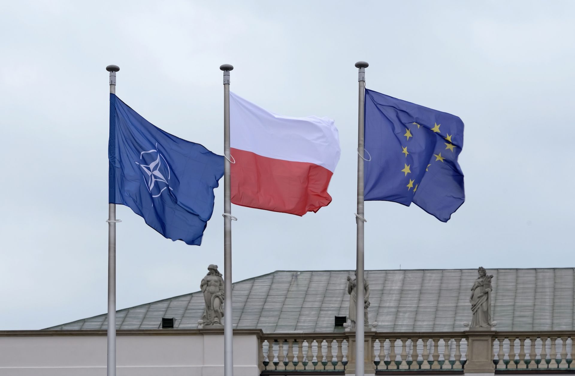 The flags of NATO, the EU and Poland are seen next to each other. 