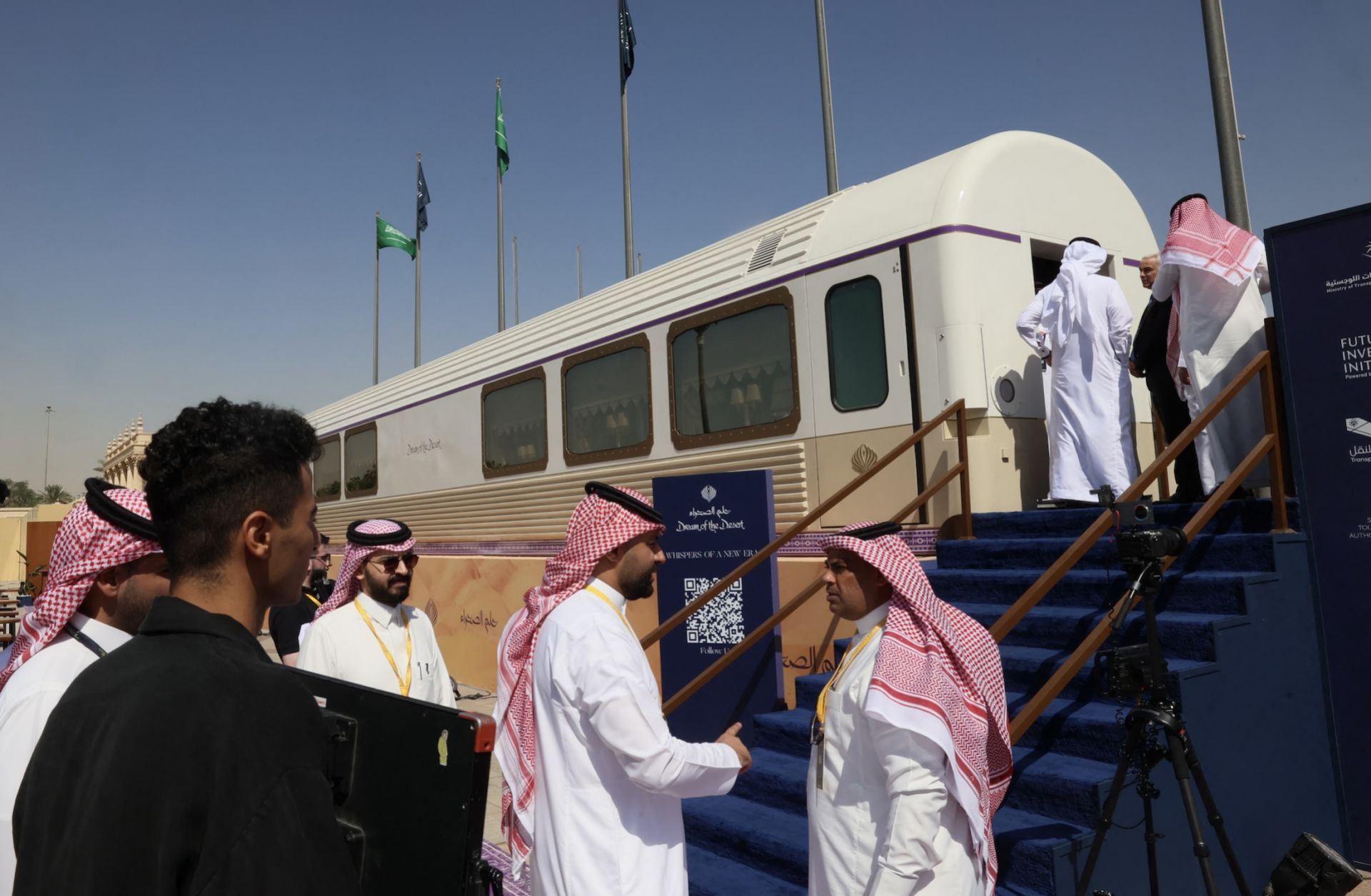 Guests stand outside a model carriage of the "Dream of the Desert" ultra-luxury train on display during the Future Investment Initiative conference in Riyadh, Saudi Arabia, on Oct. 28, 2025.