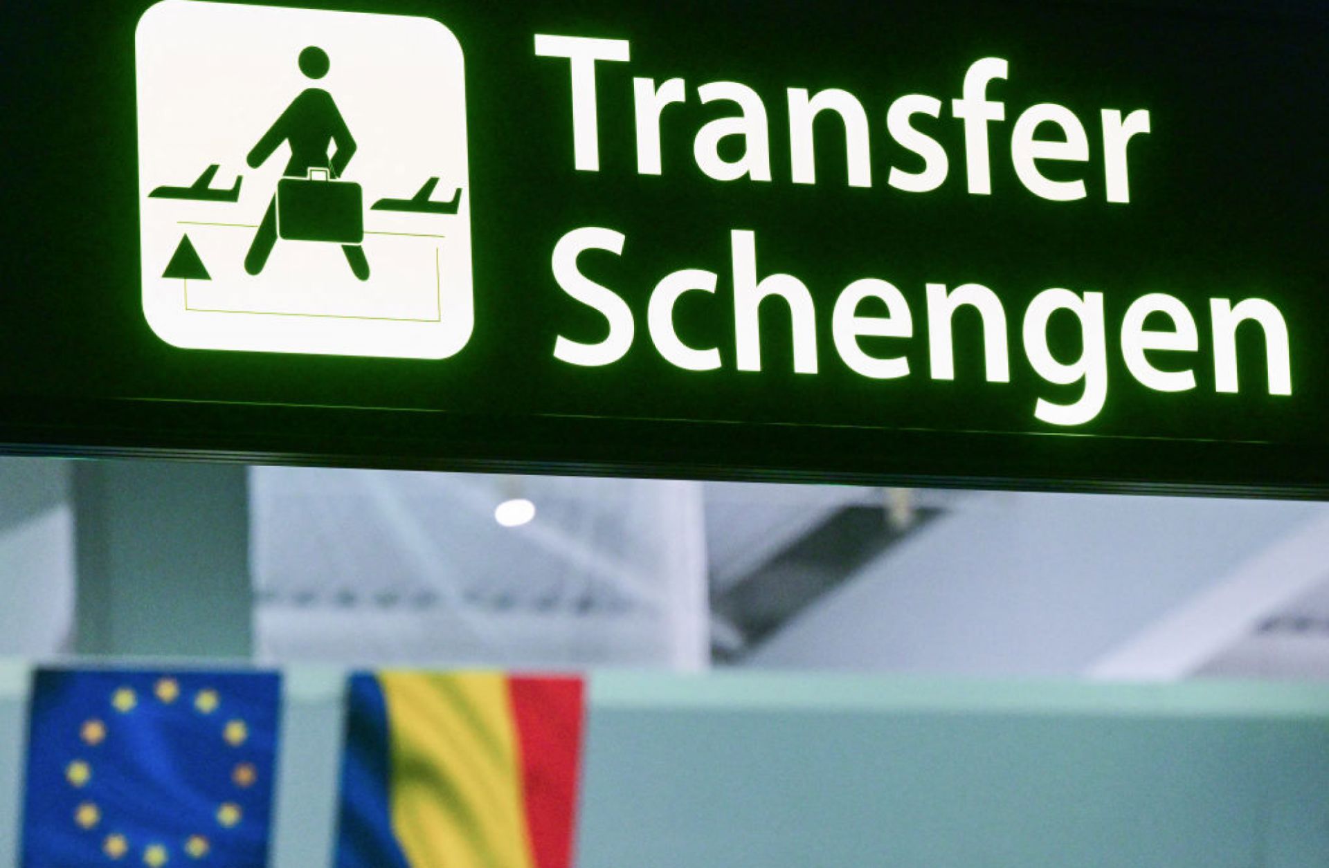 A newly installed sign pointing to Schengen transfer flights is pictured next to EU and Romanian flags on March 31, 2024. 