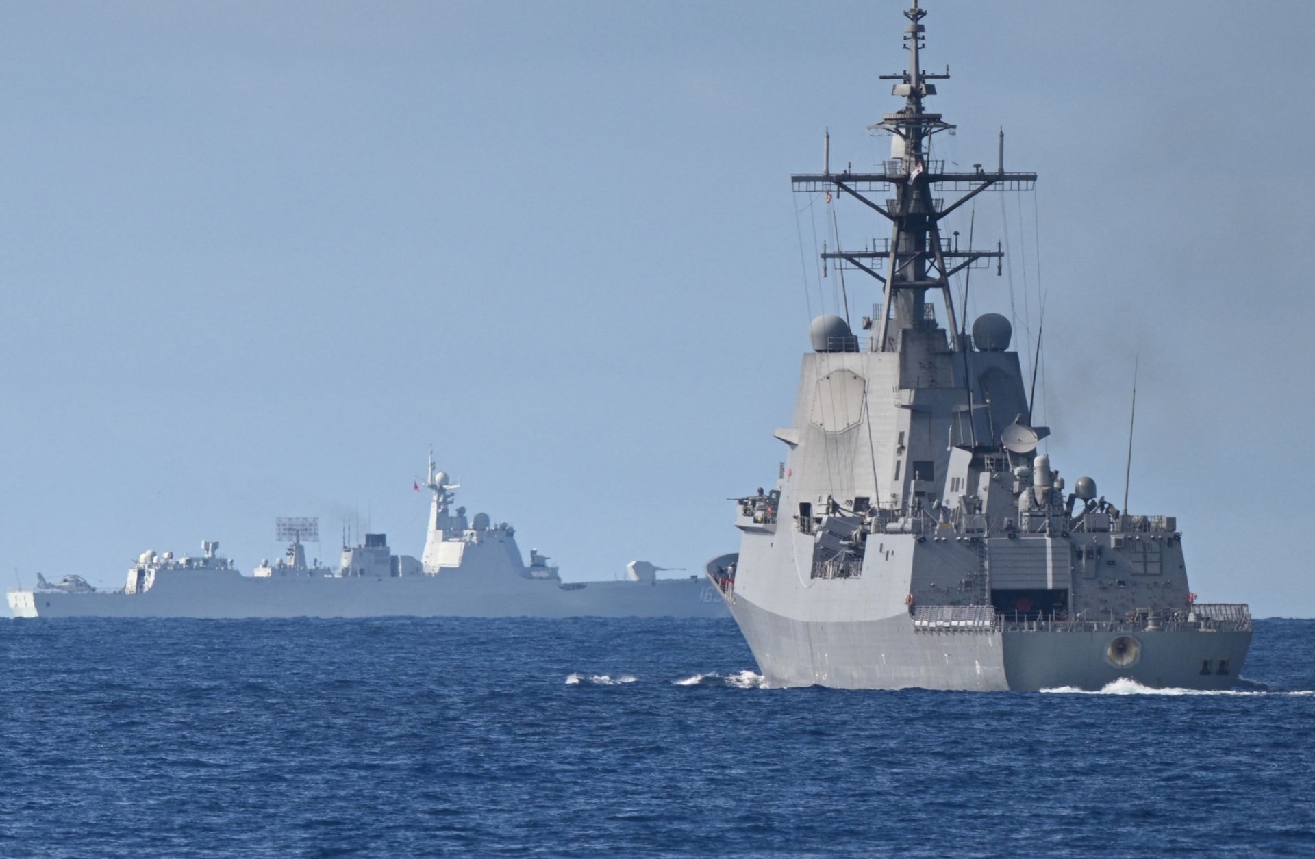 A Chinese navy ship (background left) is seen while an Australian navy ship (right) takes part in a maritime cooperative activity with the Philippines and Canada in the disputed waters of the South China Sea on Sept. 3, 2025.