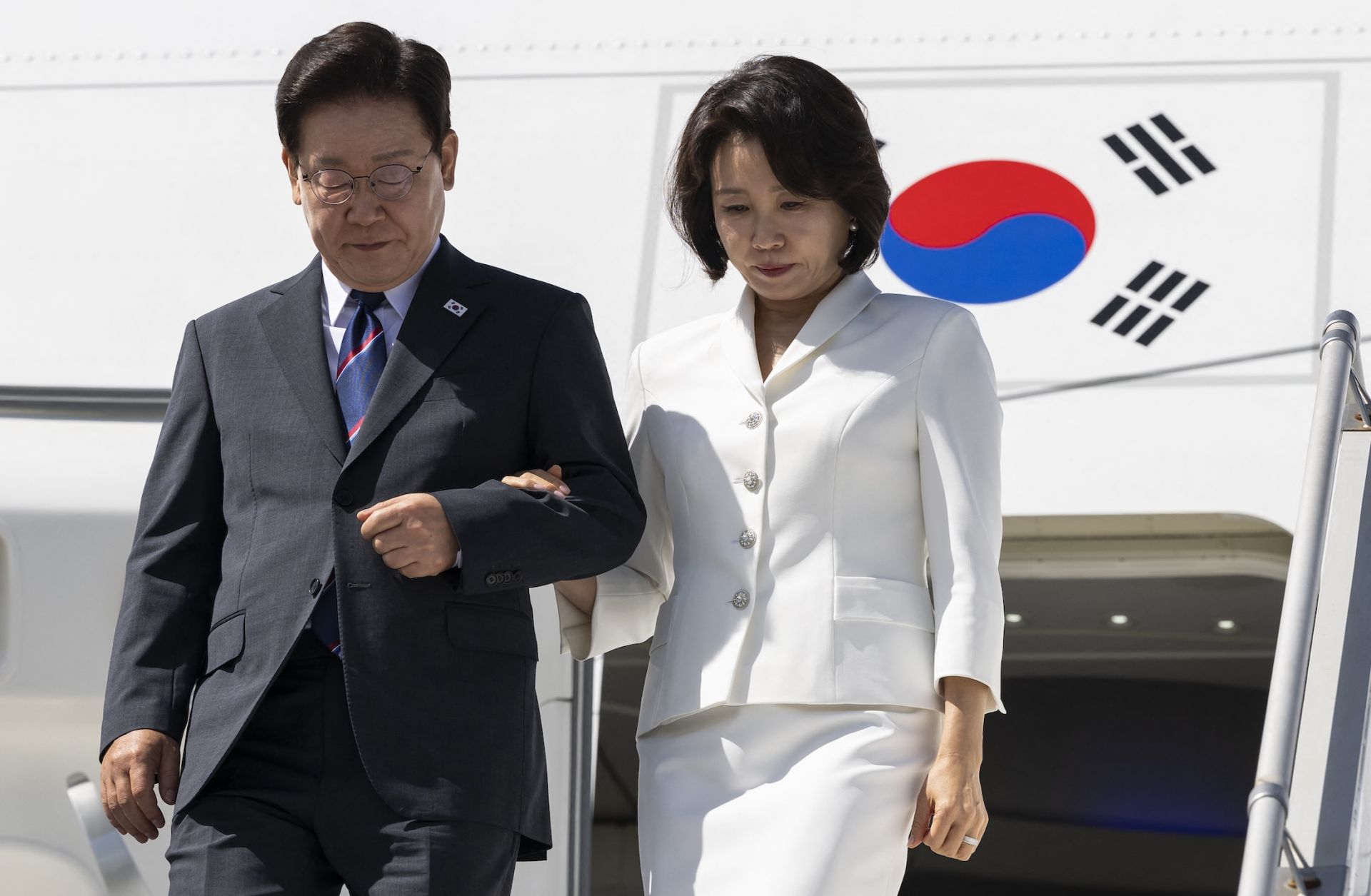 South Korean President Lee Jae Myung (left) and his wife disembark from the plane at Geneva Airport as they arrive to attend the G7 summit on June 16, 2026.