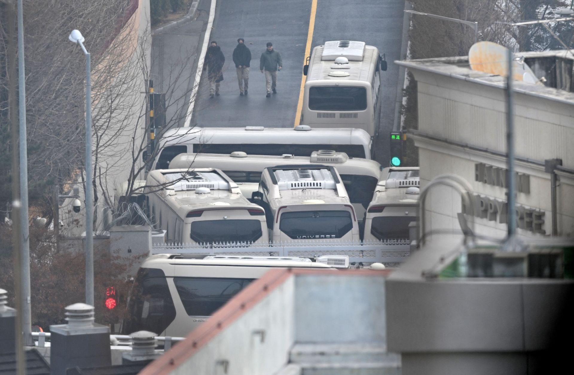 Security personnel walk on a road with buses blocking an entrance gate to protect impeached South Korean President Yoon Suk Yeol from a possible second arrest in Seoul on Jan. 6.